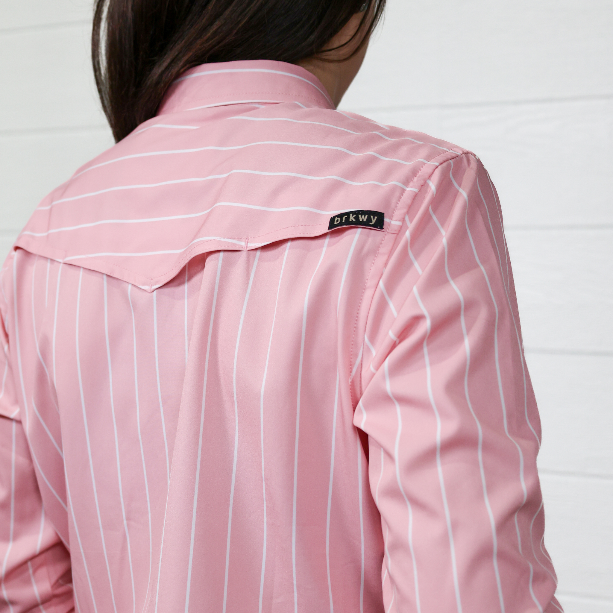 Pink striped shirt with a brand label on a white background showing the vent