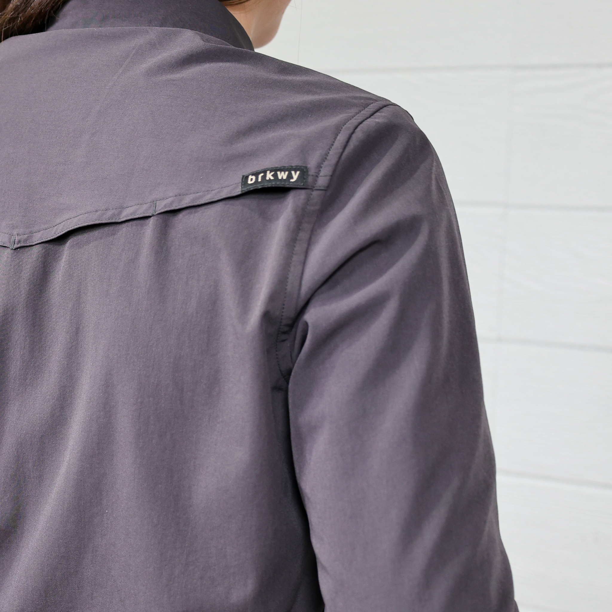 Gray  women's button down with a brand label on the shoulder against a white background