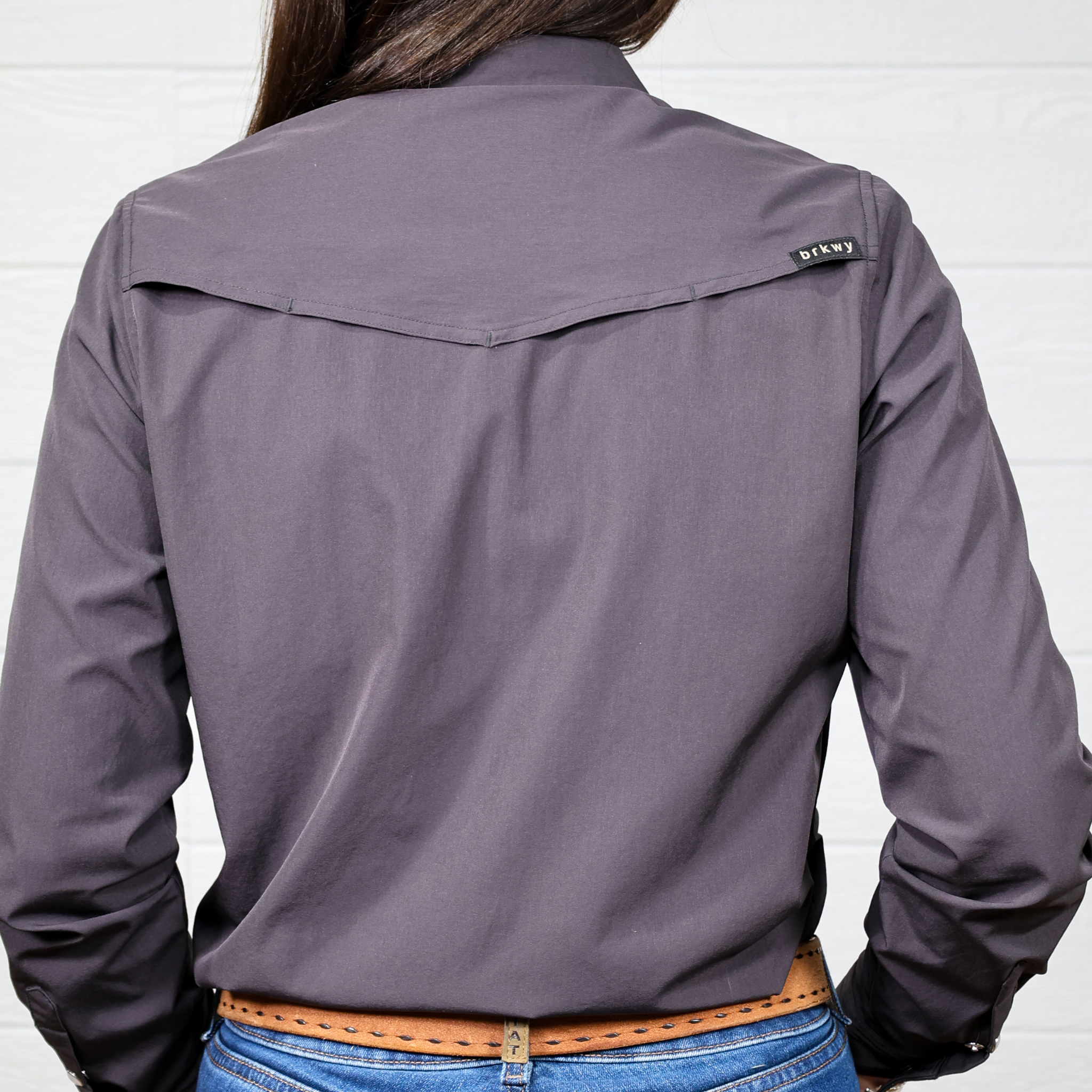 Person wearing a dark gray shirt with a brand logo on a white background