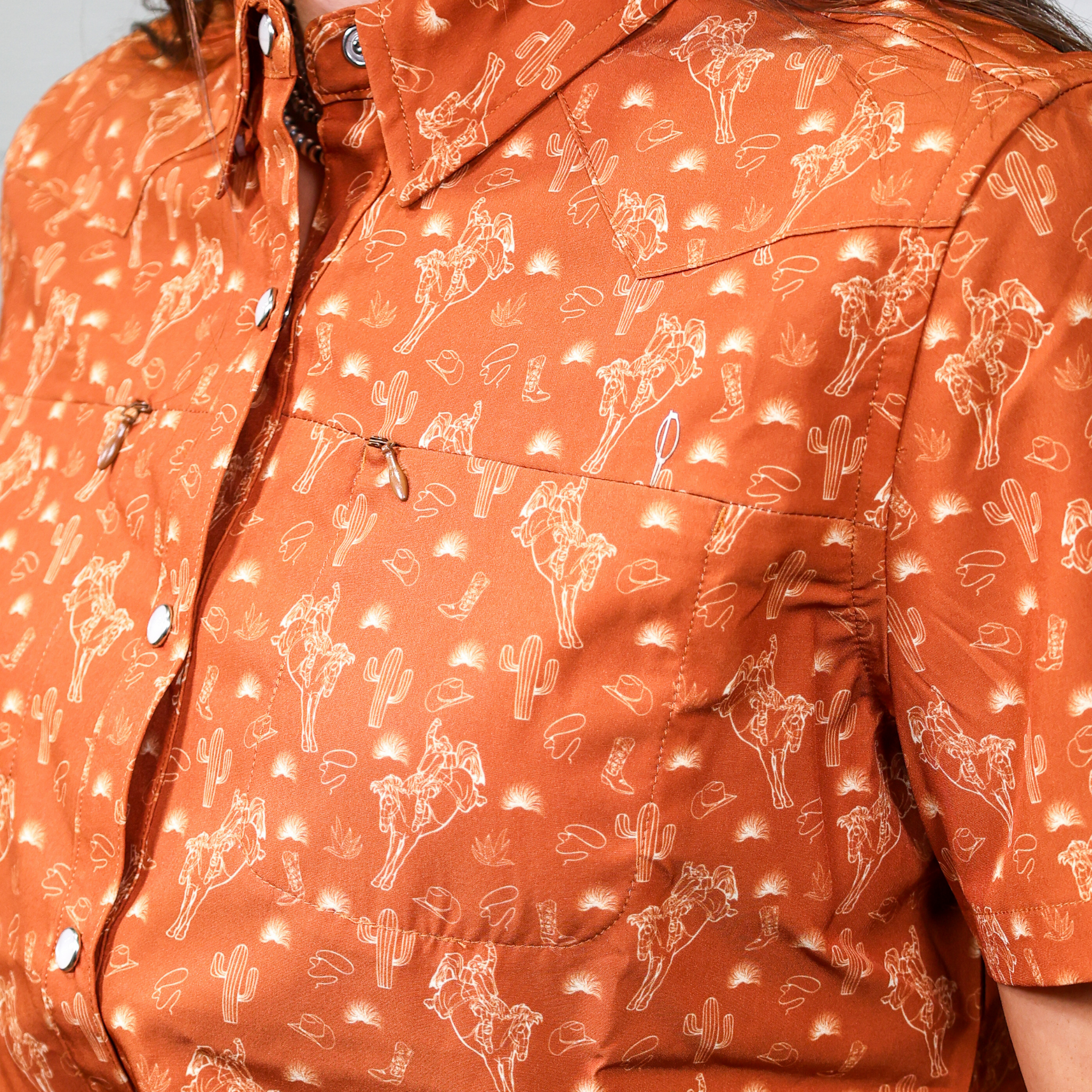 Close-up of a women's orange shirt with white patterns on a white background. Pocket Detail.
