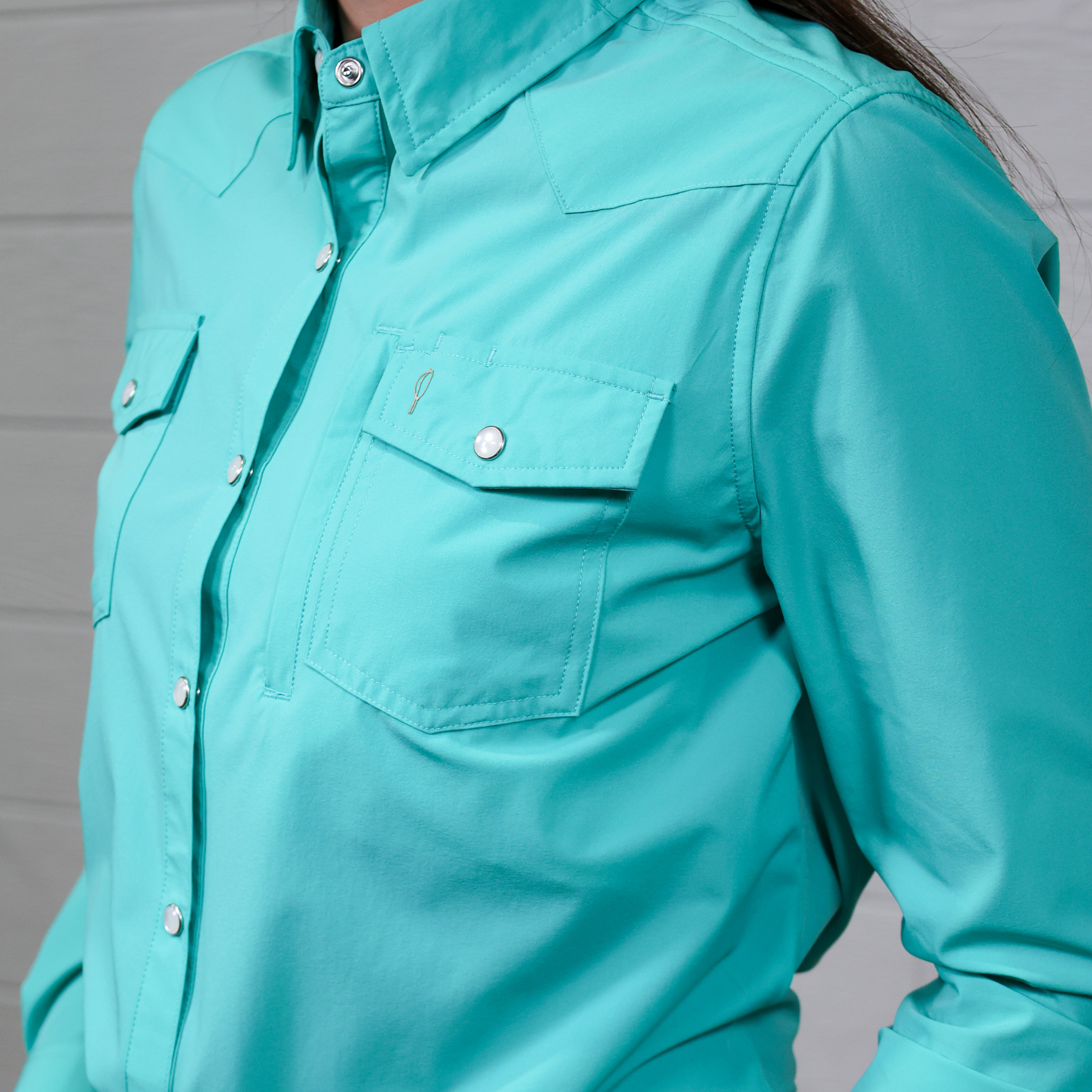 Close-up of a turquoise shirt with button details on a white background.
