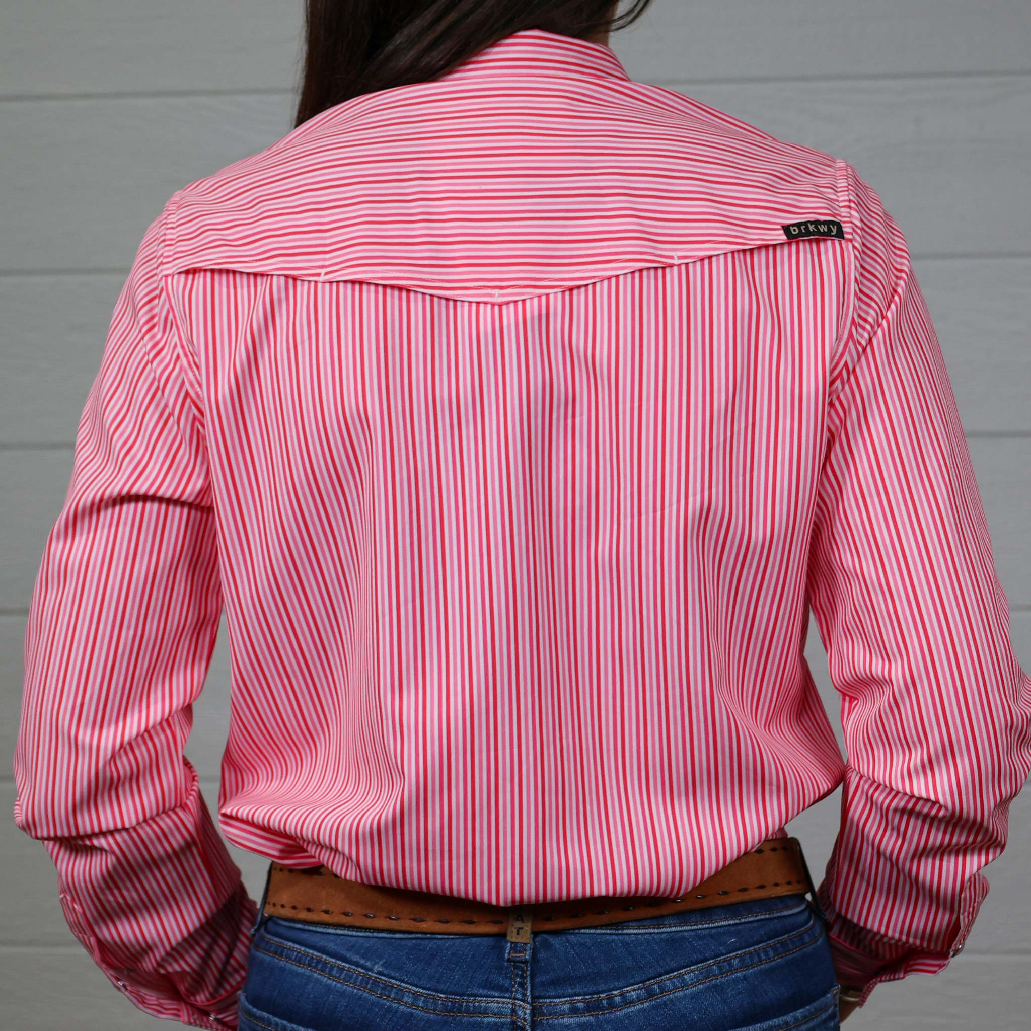 Person wearing a pink and white striped shirt with a White Background. Back Facing