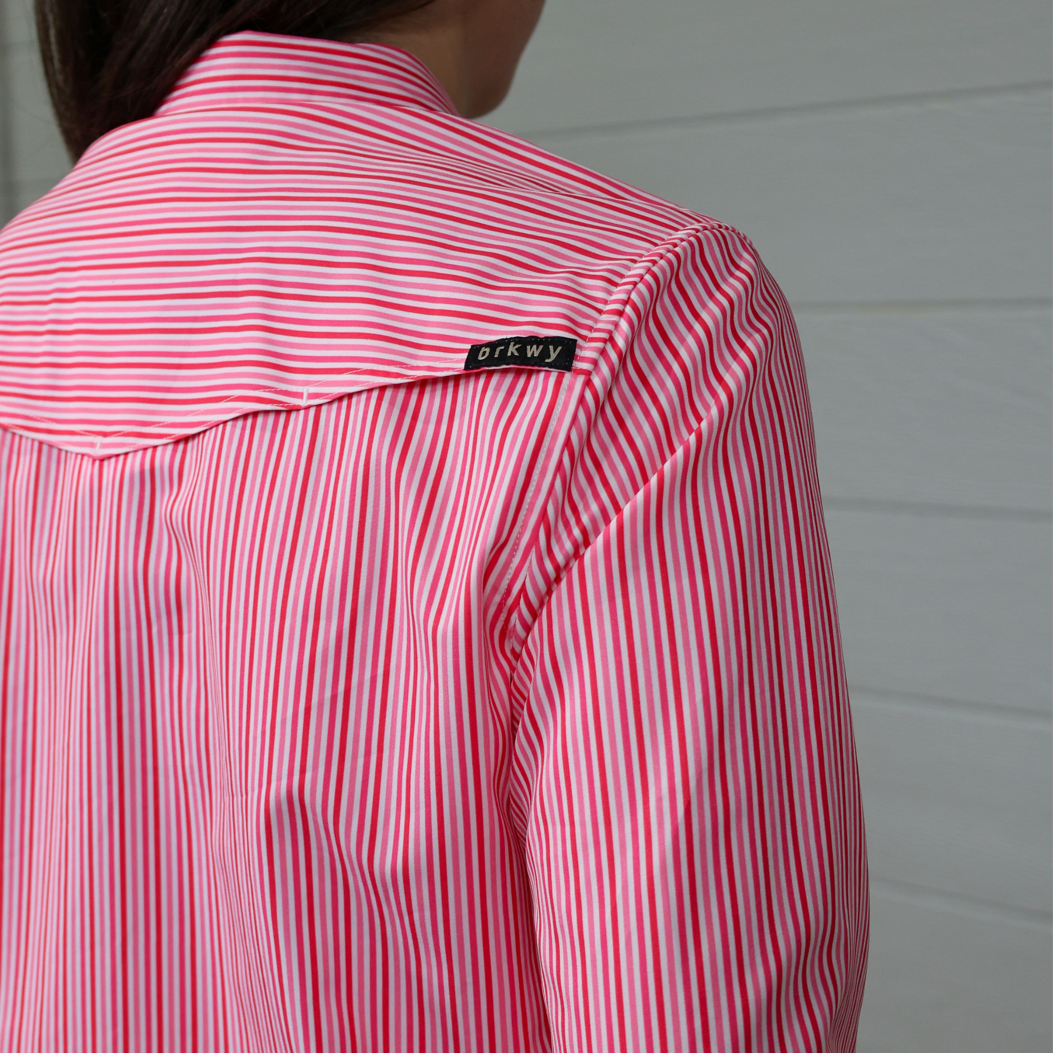 pink and white striped shirt with a brand label on a white background