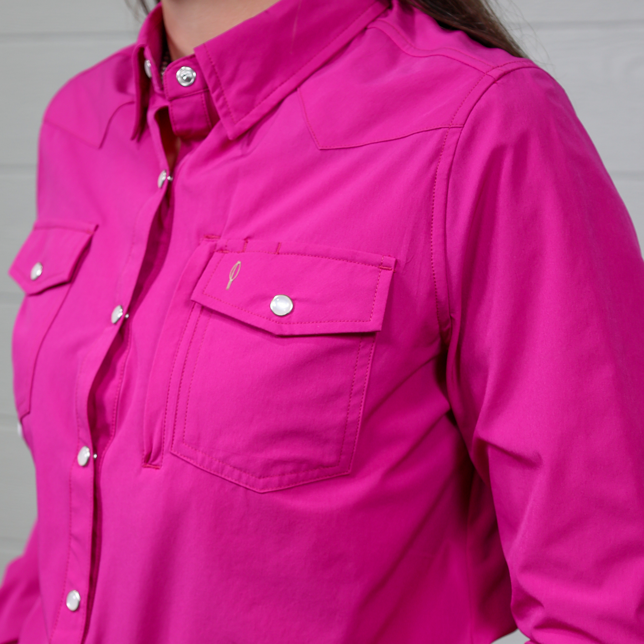 Close-up of a bright pink shirt with button details on a white background.