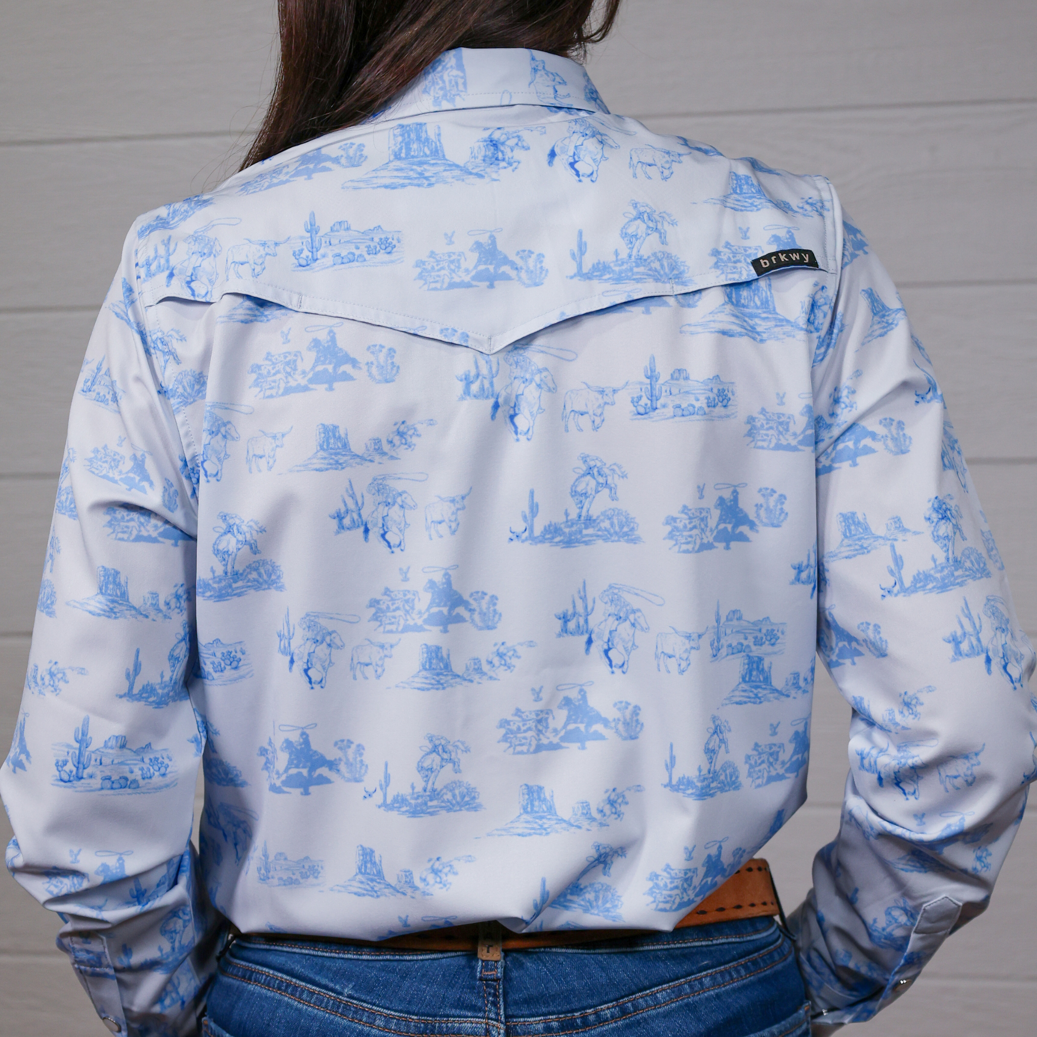 Person wearing a light blue shirt with a blue pattern against a white background. back facing.