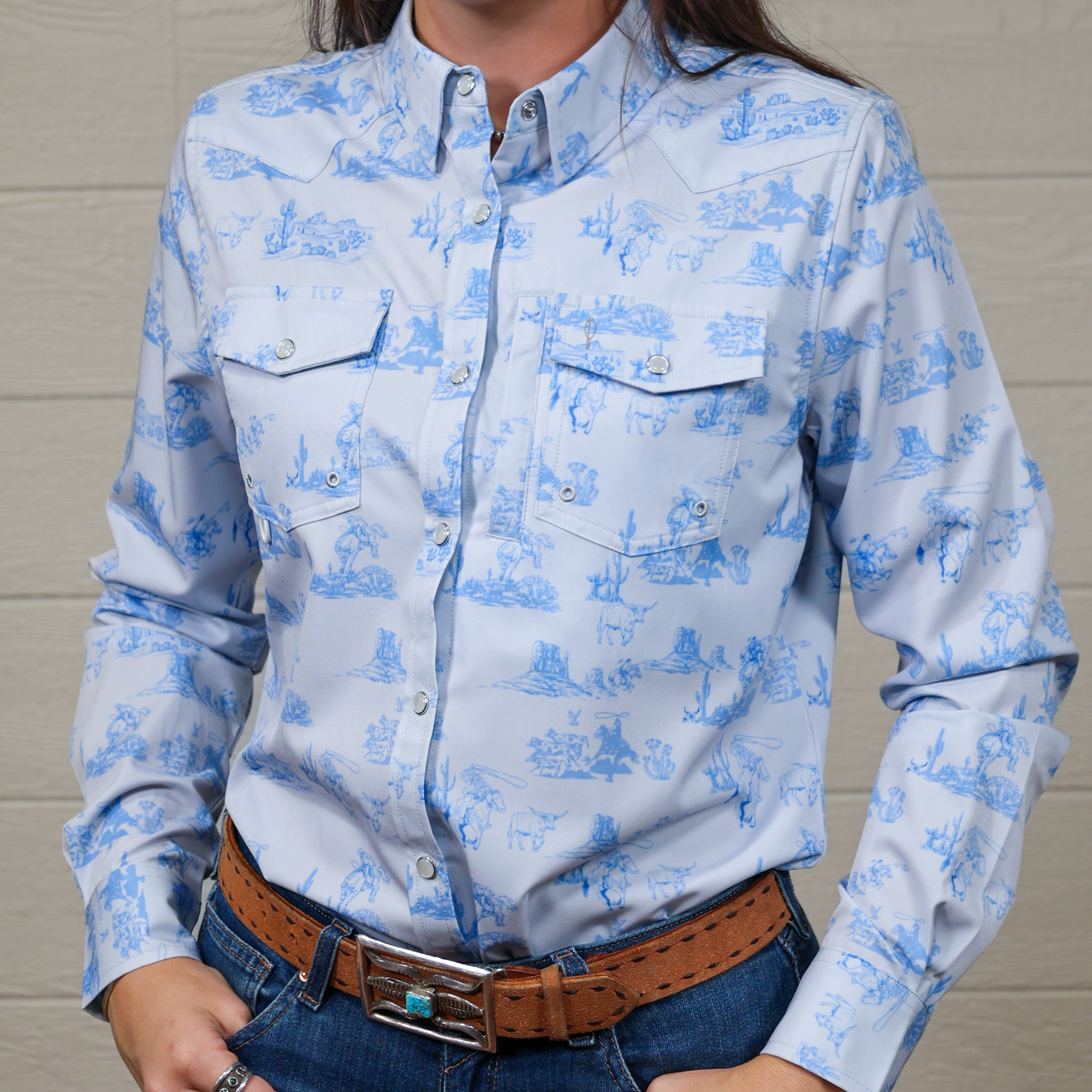 Person wearing a blue patterned shirt with a brown belt against a white background. front facing.