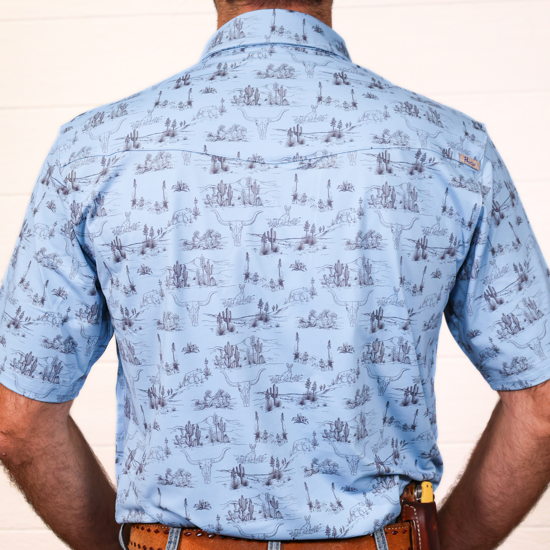 Light blue patterned polo worn by a person on a plain background showing the back