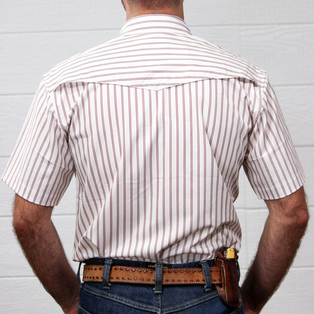 Rear view of a man wearing a short-sleeve western-style button-up shirt with thin vertical red stripes on a white background, paired with a brown studded belt and jeans.