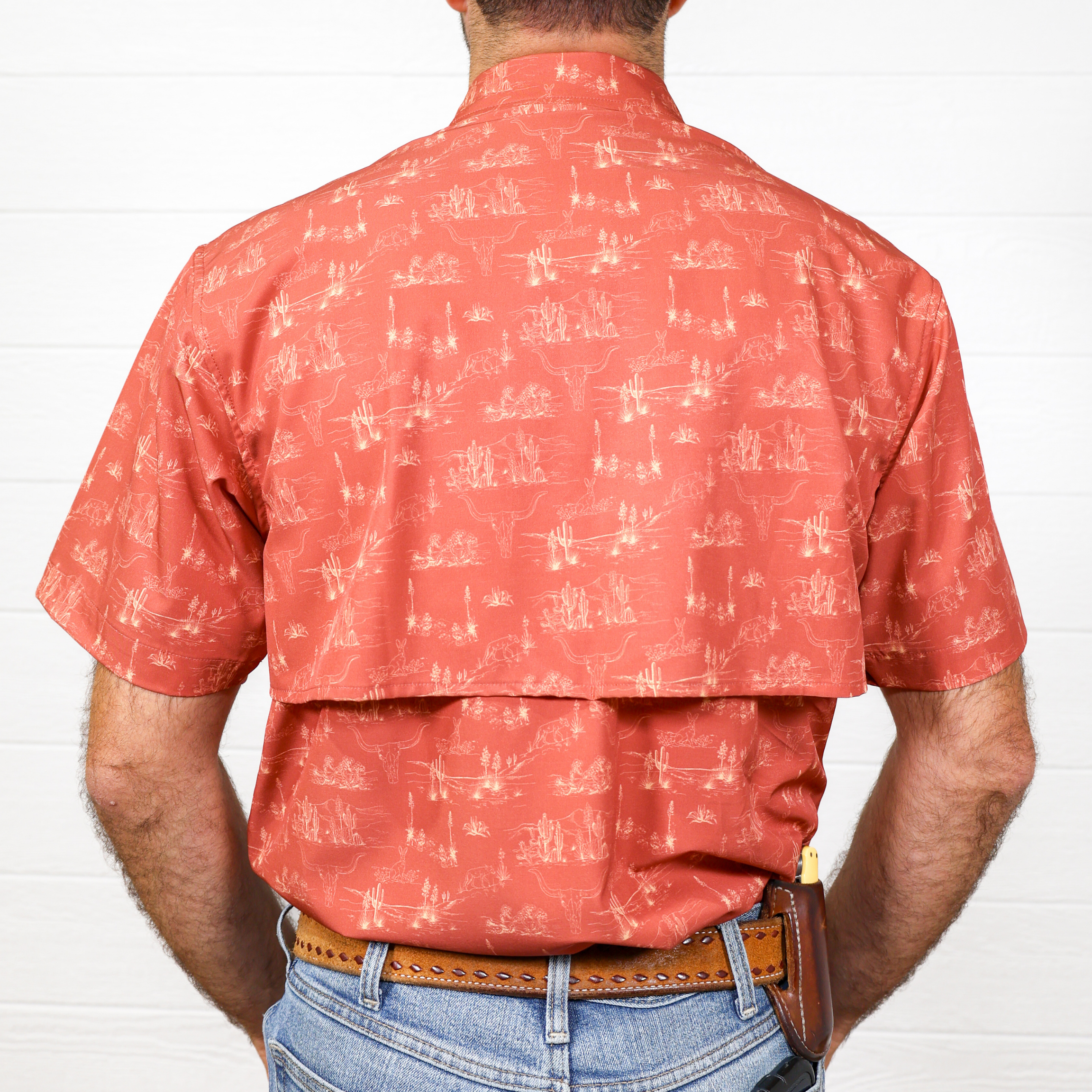 Person wearing a red patterned shirt and blue jeans against a white  background showing the back