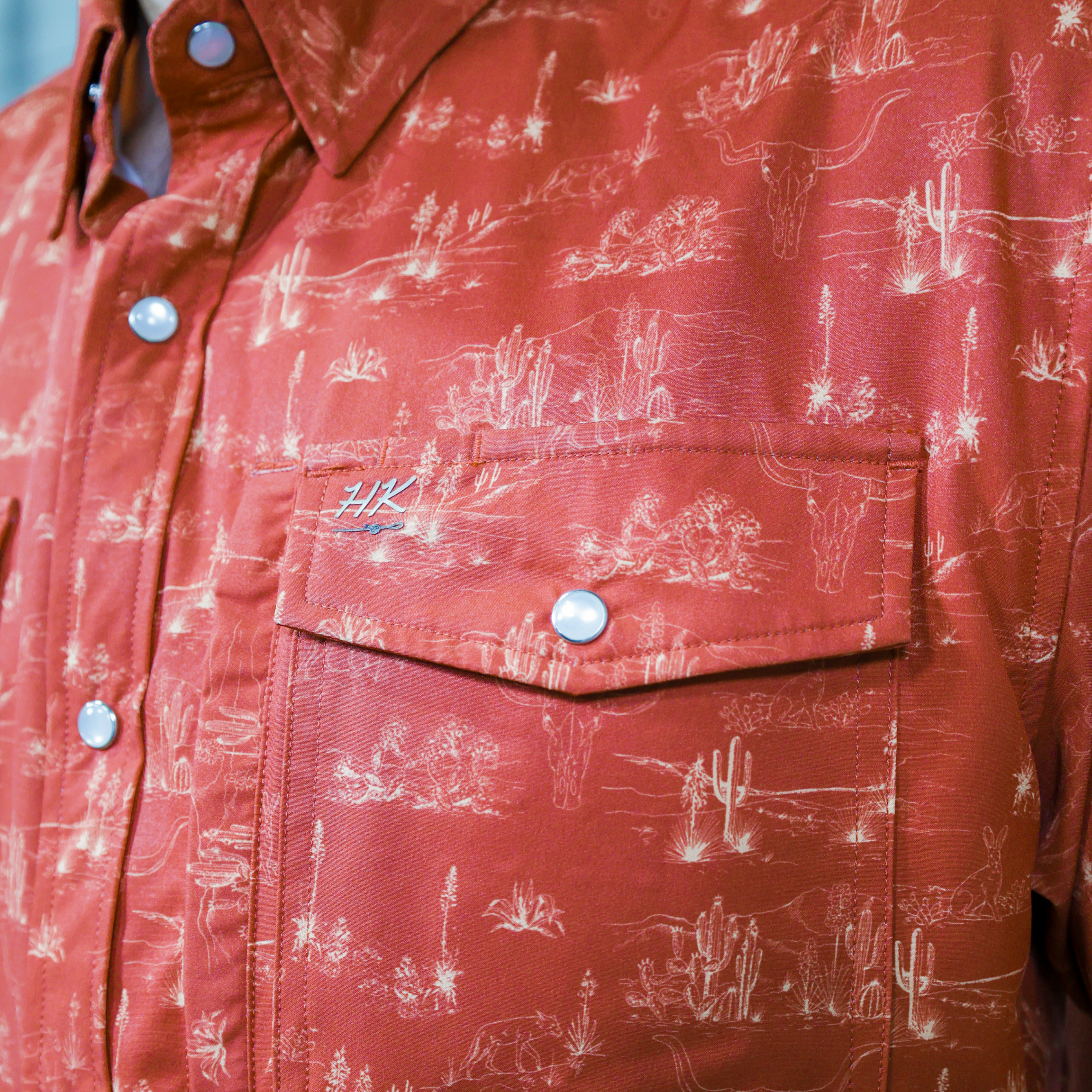 Orange shirt with white patterns and brand logo on the pocket on a white background
