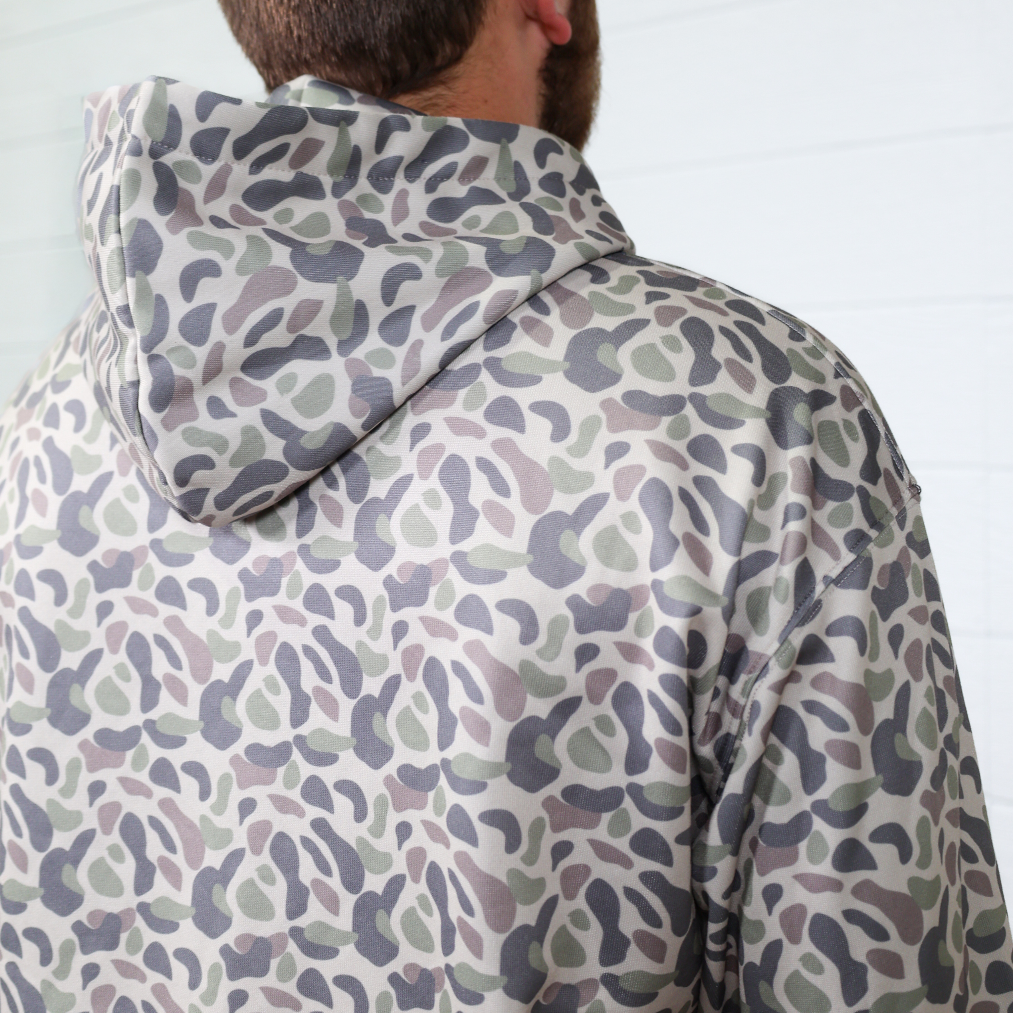 Person wearing a patterned raincoat with a white background showing the hood 