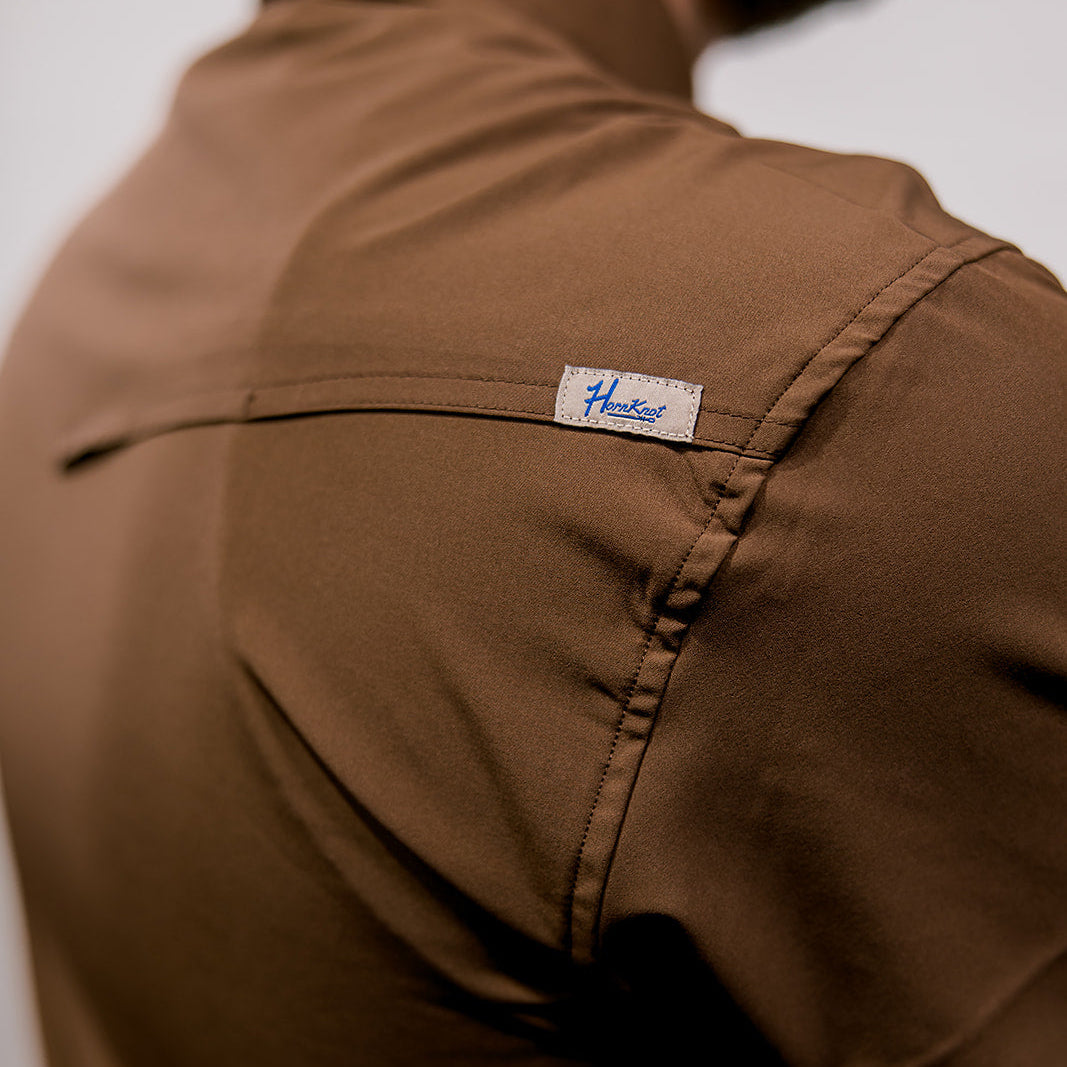 Brown shirt with a brand label on a neutral background