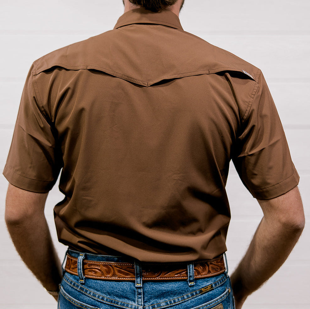 Man wearing a brown shirt and blue jeans against a white background. Back Facing.