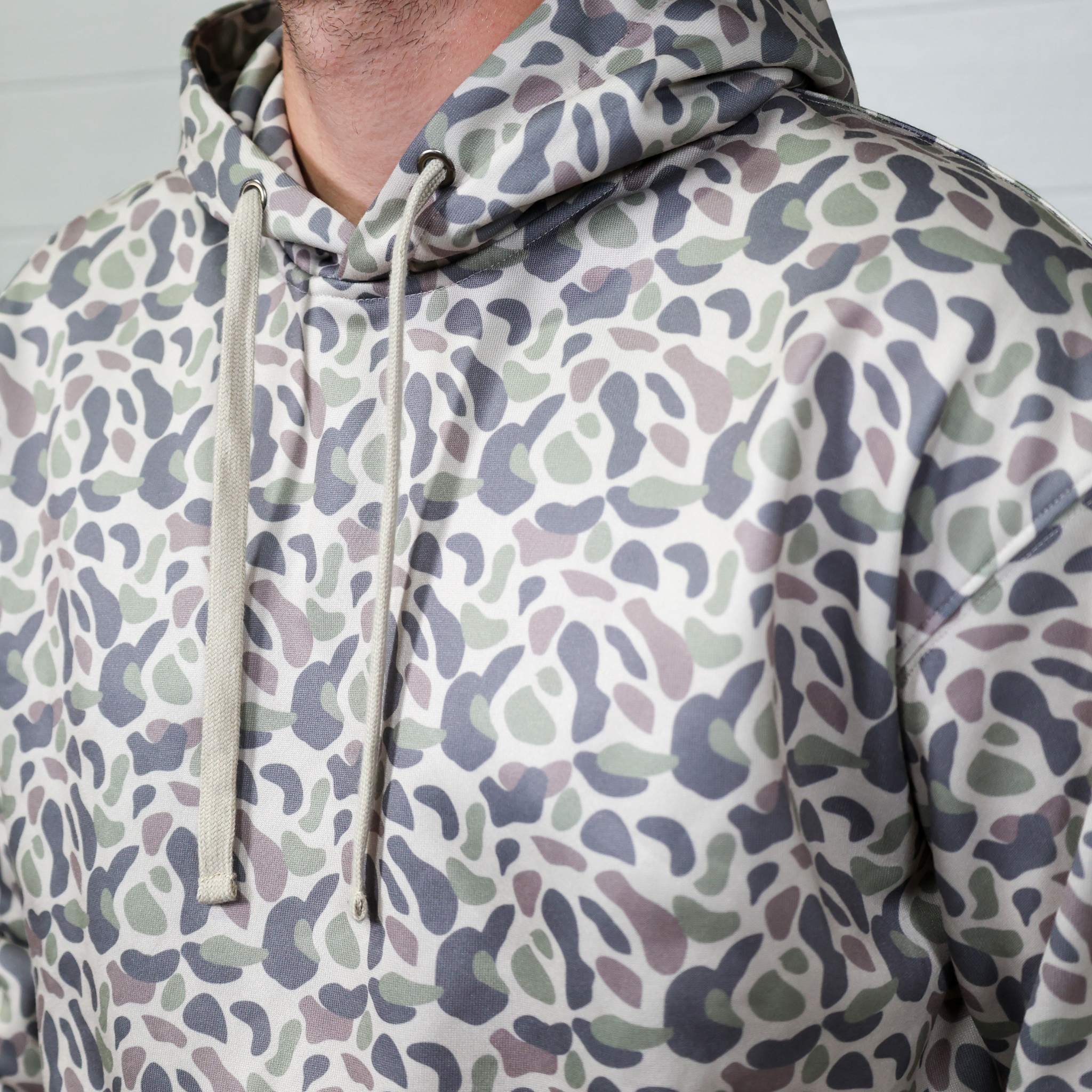 Person wearing a patterned hoodie with a neutral background showing the drawstrings 