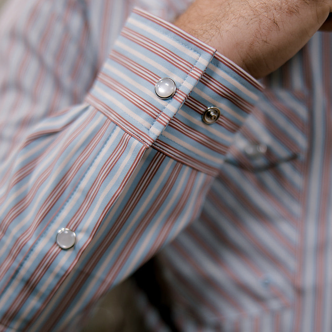 Close-up of a striped shirt with rolled-up sleeves and visible buttons.
