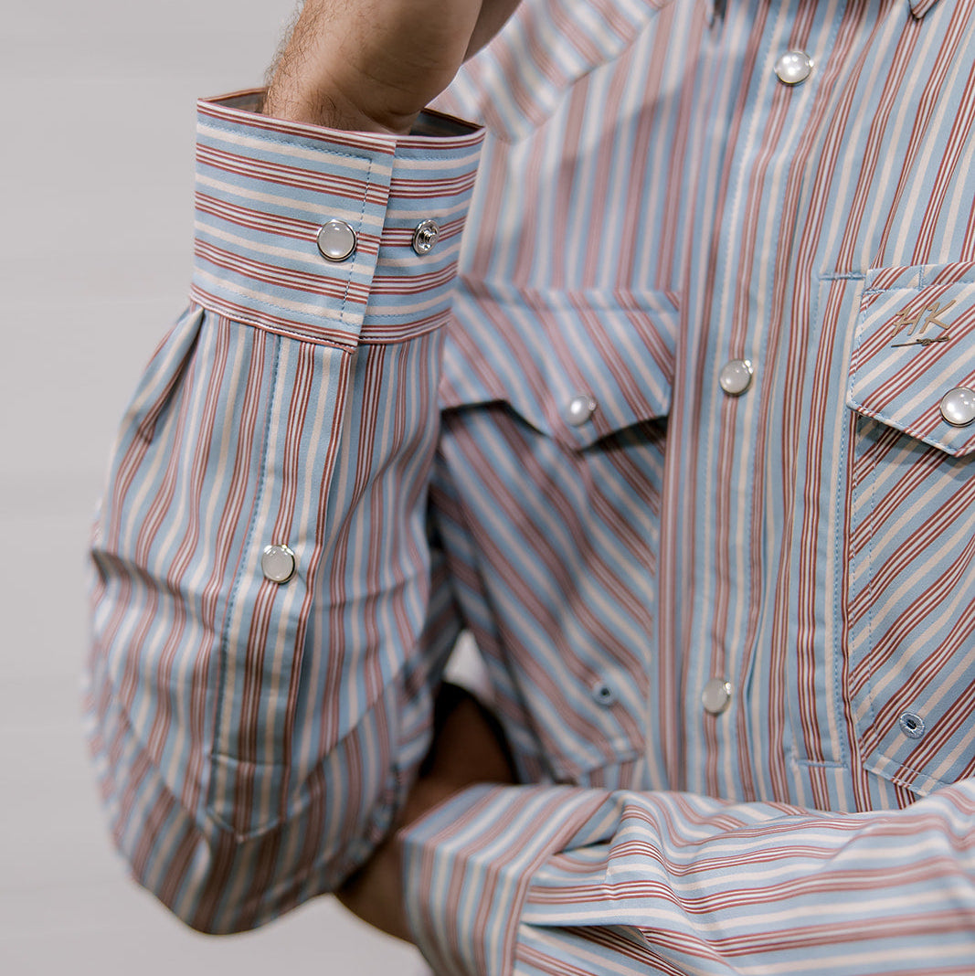Close-up of a person wearing a striped shirt with rolled-up sleeves. Cuff Detail. 
