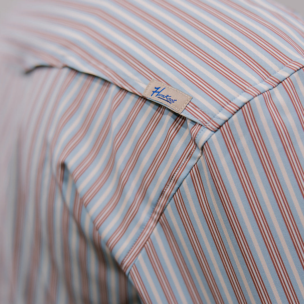Close-up of a striped shirt with a brand label on a neutral background