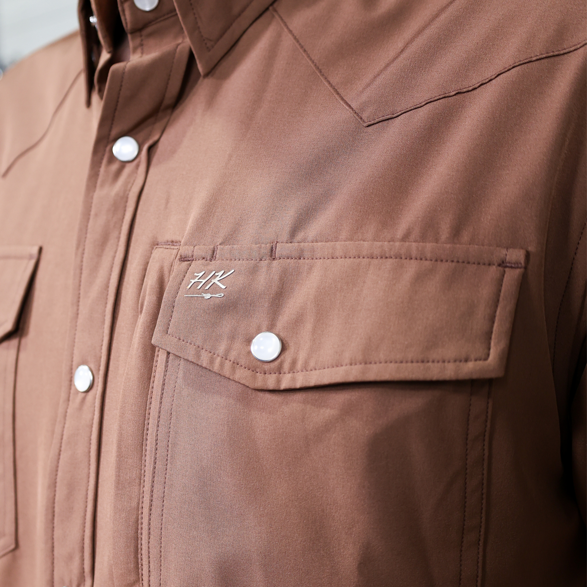 Brown shirt with a brand logo on the chest pocket