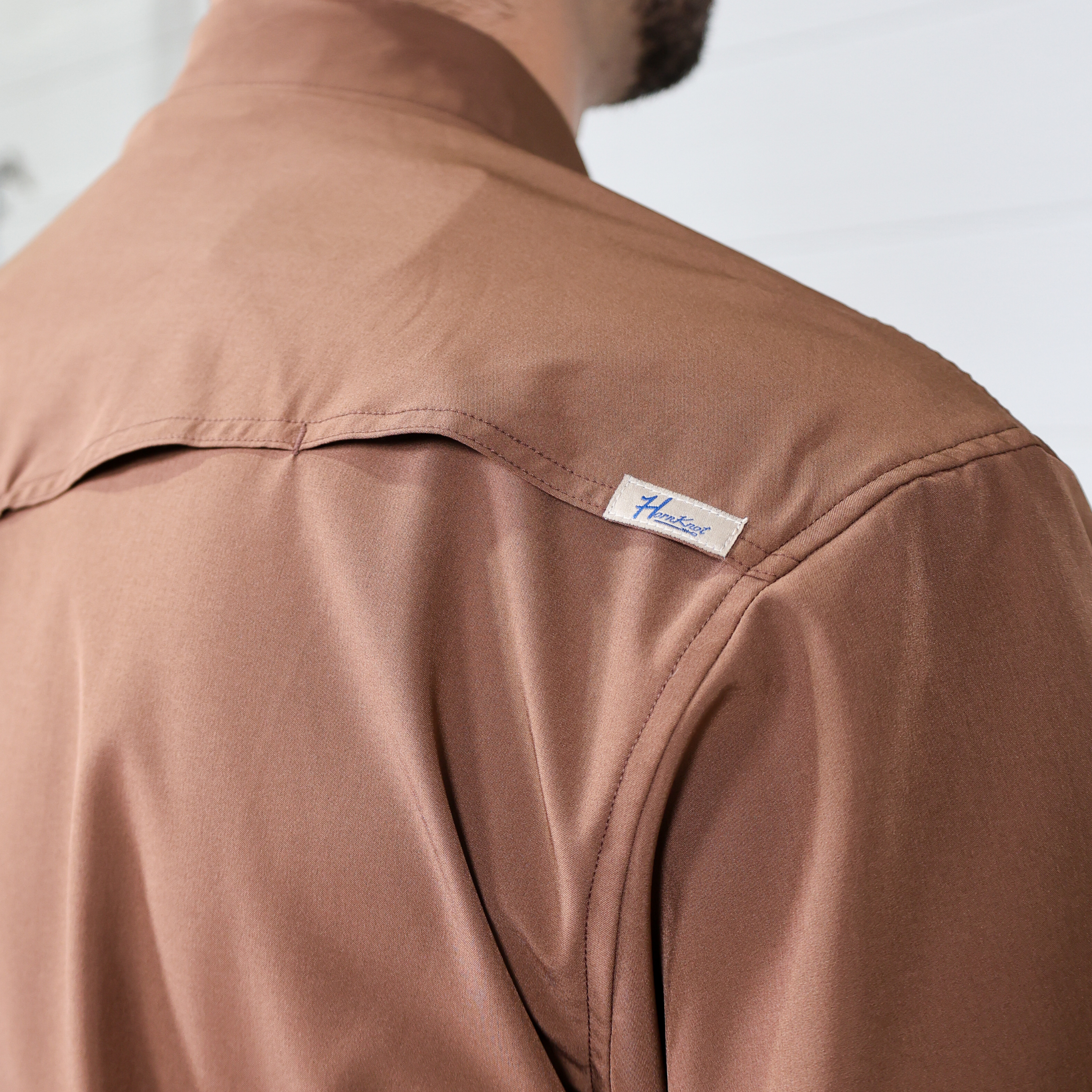 Brown short sleeve shirt with a visible brand label on the vent background