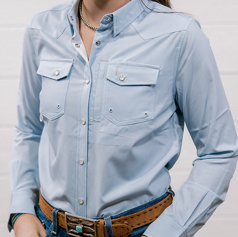 Woman wearing a light blue shirt and jeans against a plain background Showing the front 