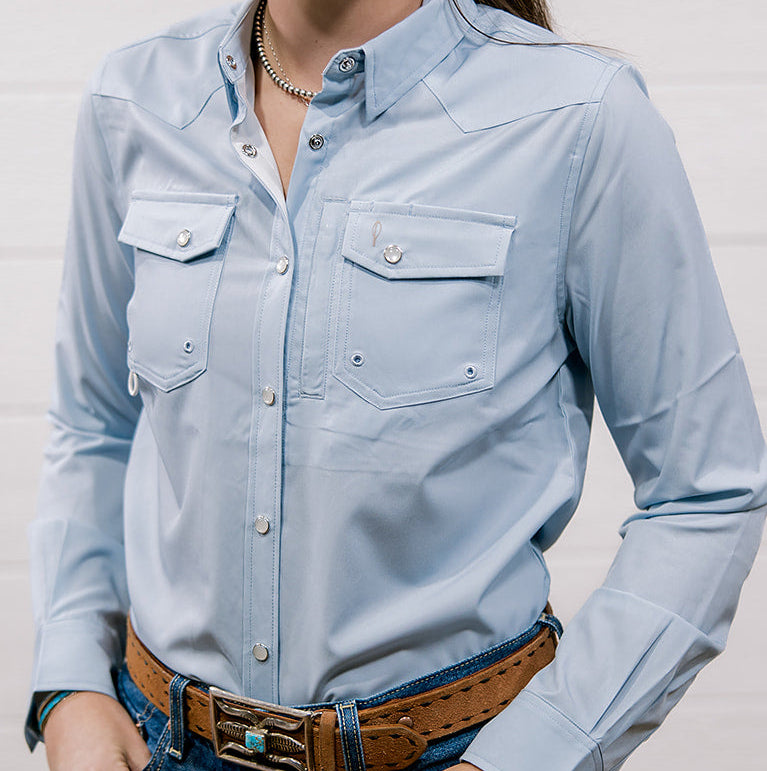 Woman wearing a light blue shirt and jeans against a plain background Showing the front 