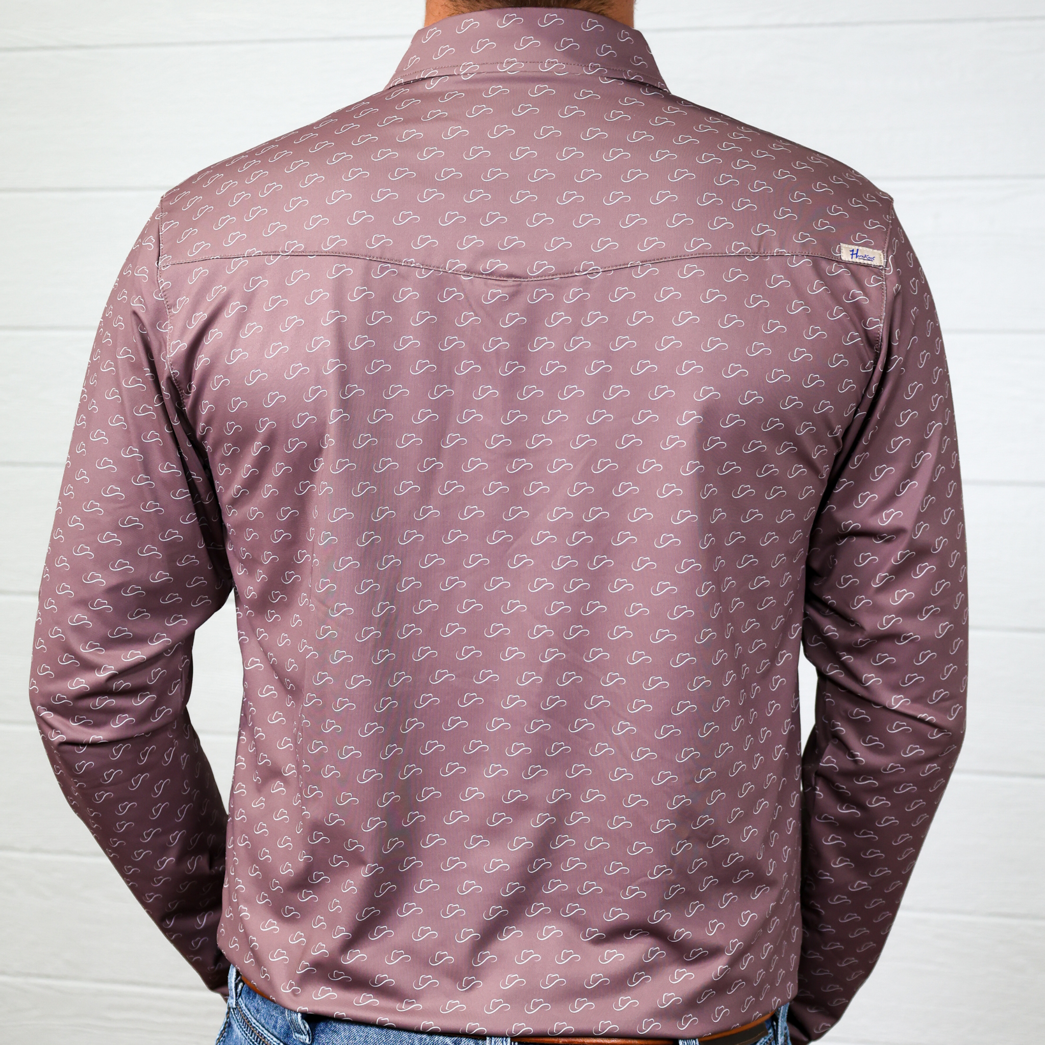 Brown patterned shirt worn by a person against a white wall showing the back 