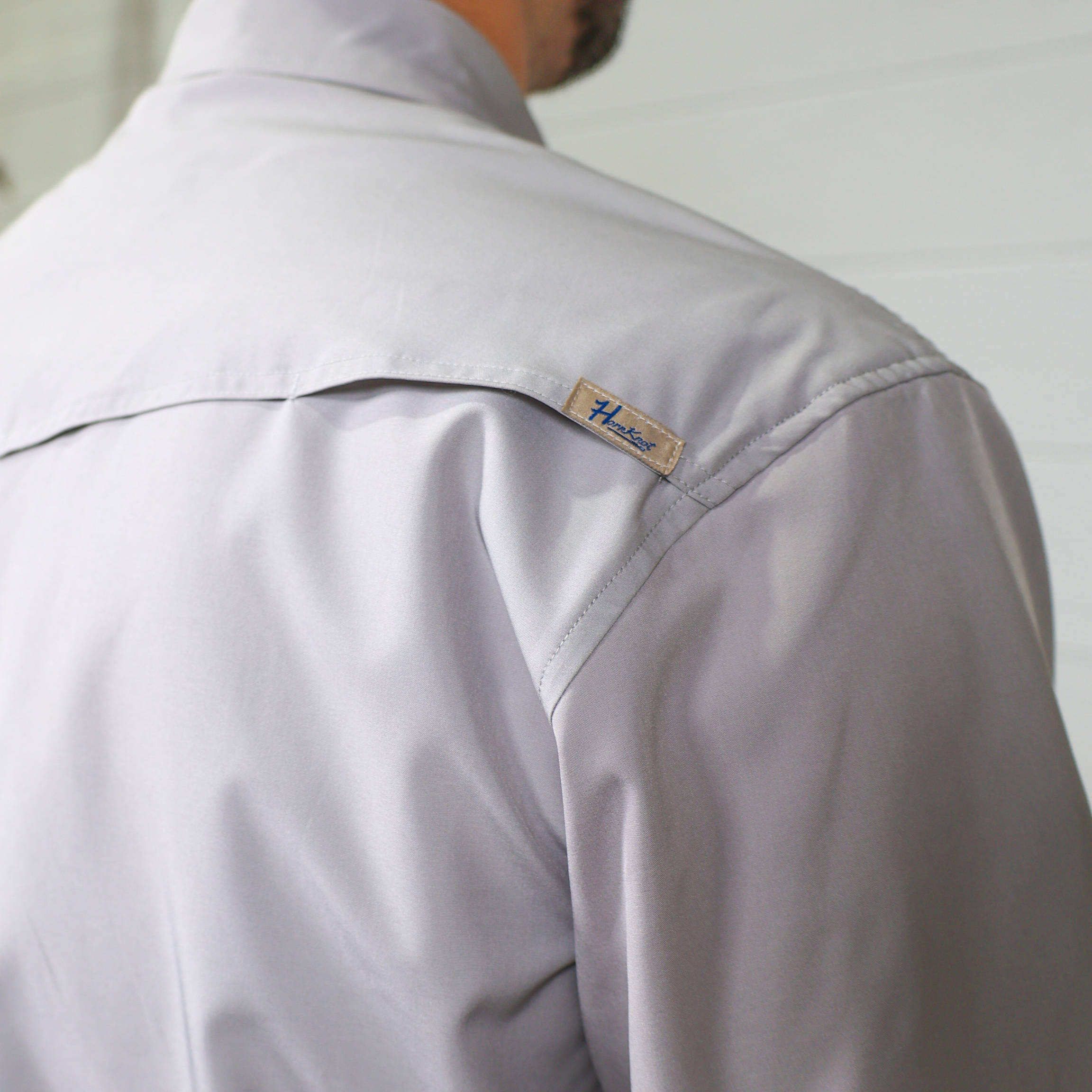 Light gray shirt with a brand logo on the shoulder against a neutral background showing the vent 
