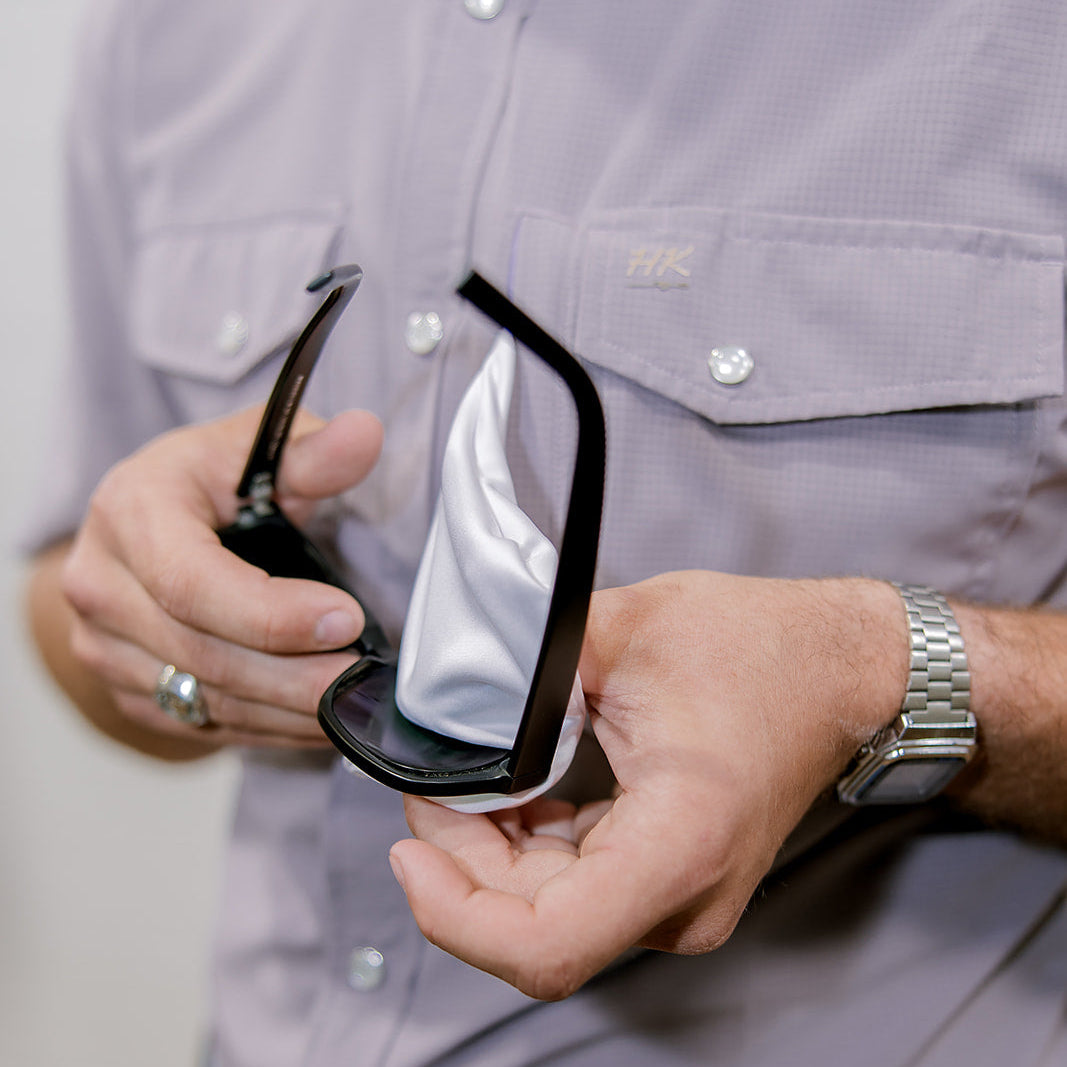 Person holding a pair of sunglasses with a neutral background showing the background 