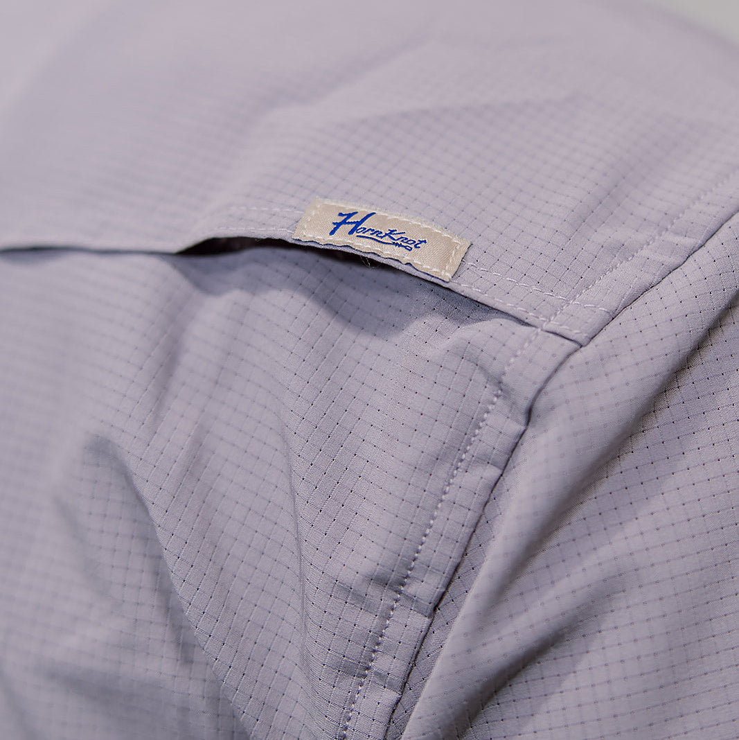 Close-up of a light purple shirt with a brand label 'Hornknot' on a plain background