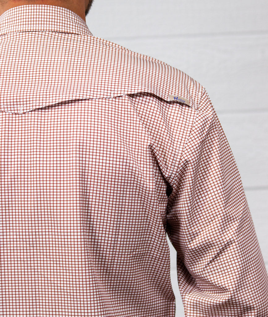 Close-up back view of a person wearing a long-sleeve button-down shirt with a fine red and white gingham check pattern, set against a light gray paneled wall.