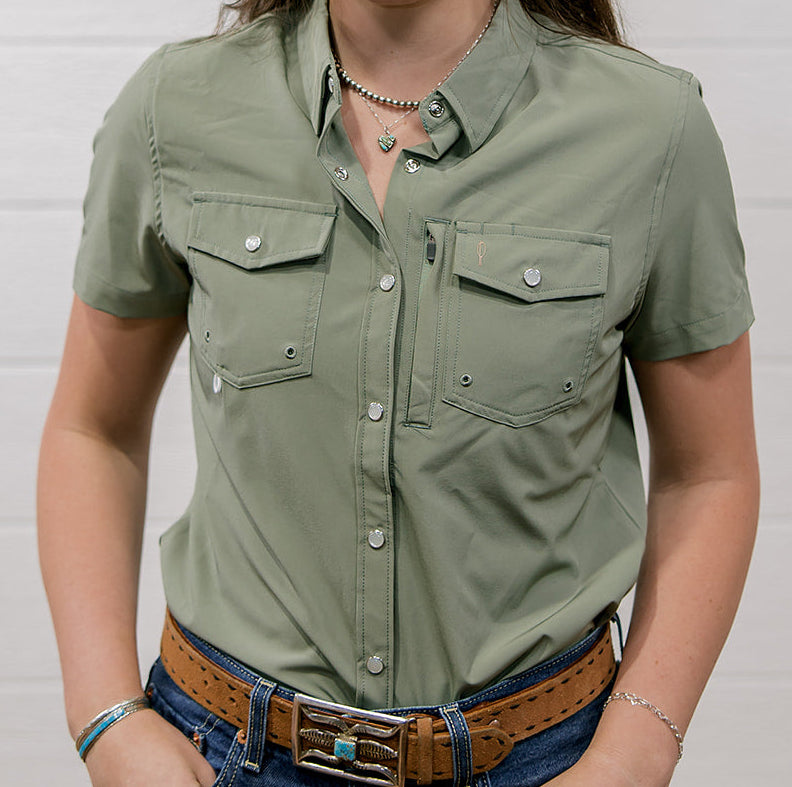 Woman wearing a sage green shirt and blue jeans against a white background showing the front 