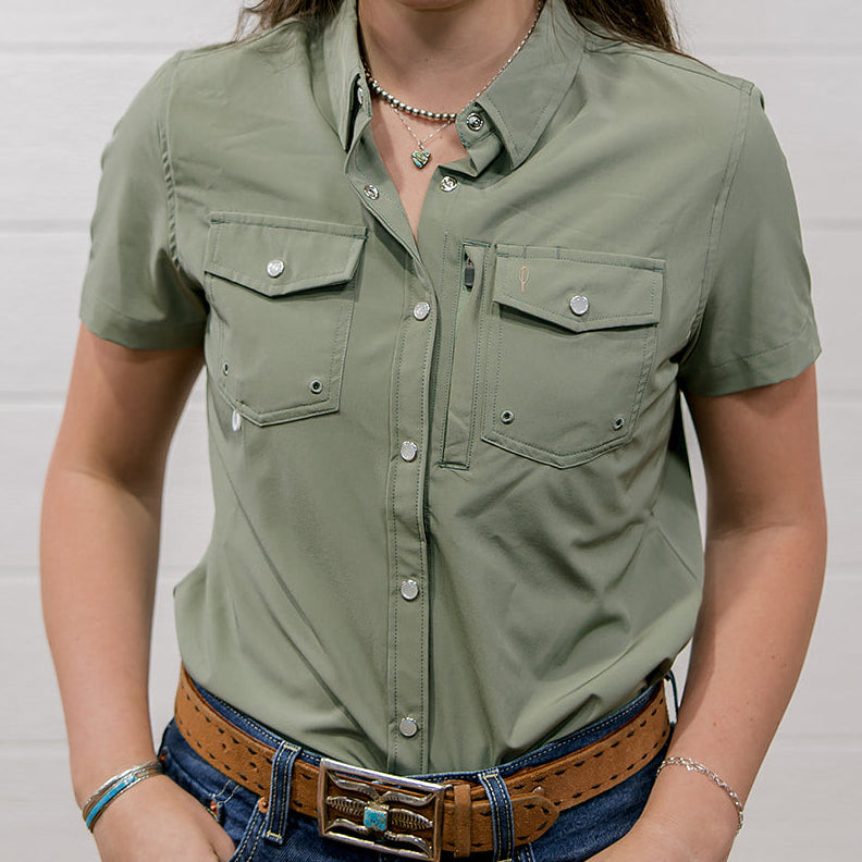 Woman wearing a sage green shirt and blue jeans against a white background showing the front 