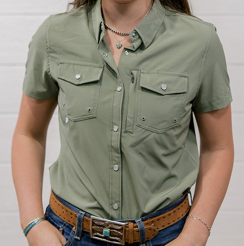 Woman wearing a sage green shirt and blue jeans against a white background showing the front 