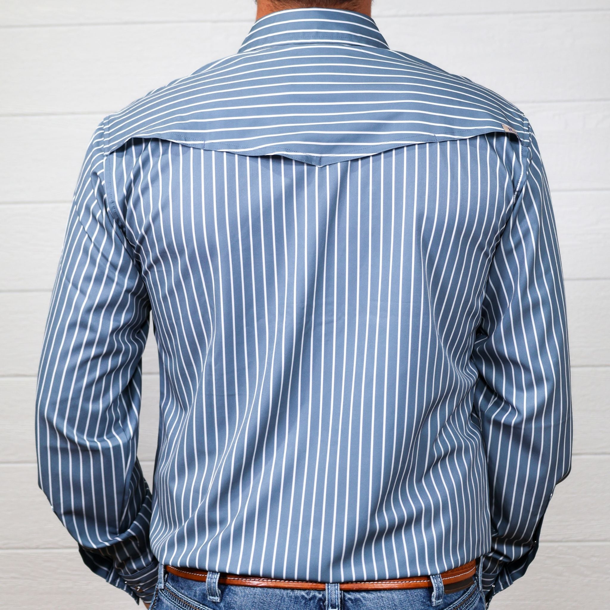 Blue and white long sleeve striped shirt worn by a person against a white background showing the back