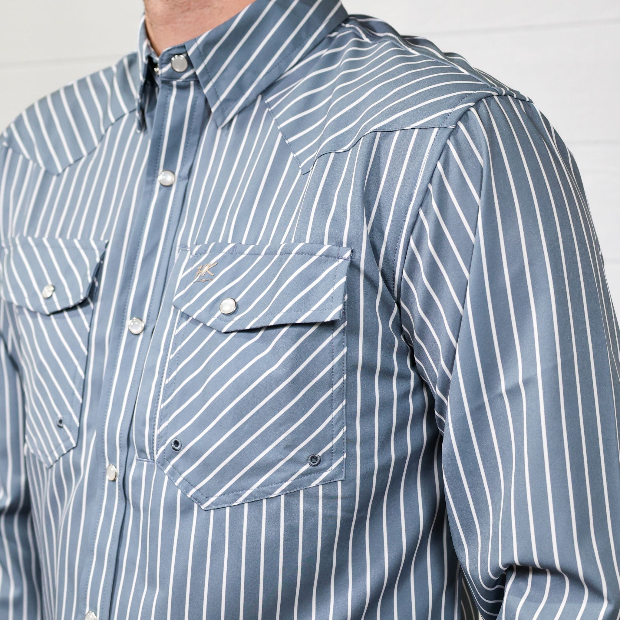 Close-up of a blue and white striped shirt with a plain background, showing the slanted pocket 