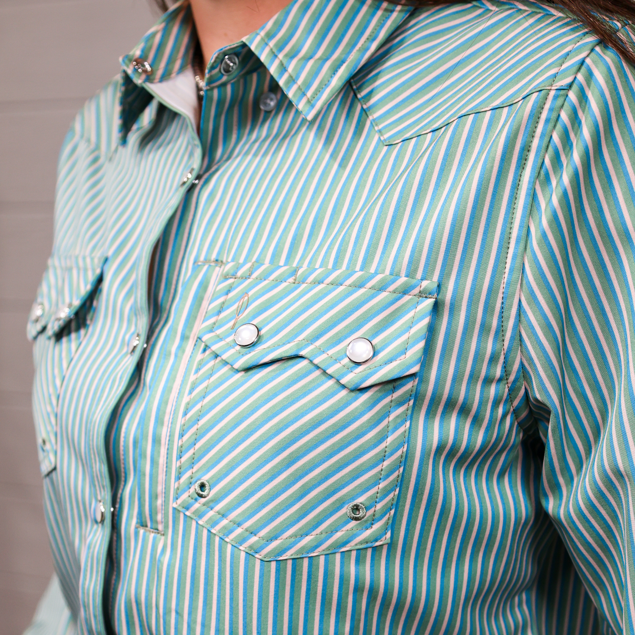 Close-up of a person wearing a green and white striped shirt with a pocket.