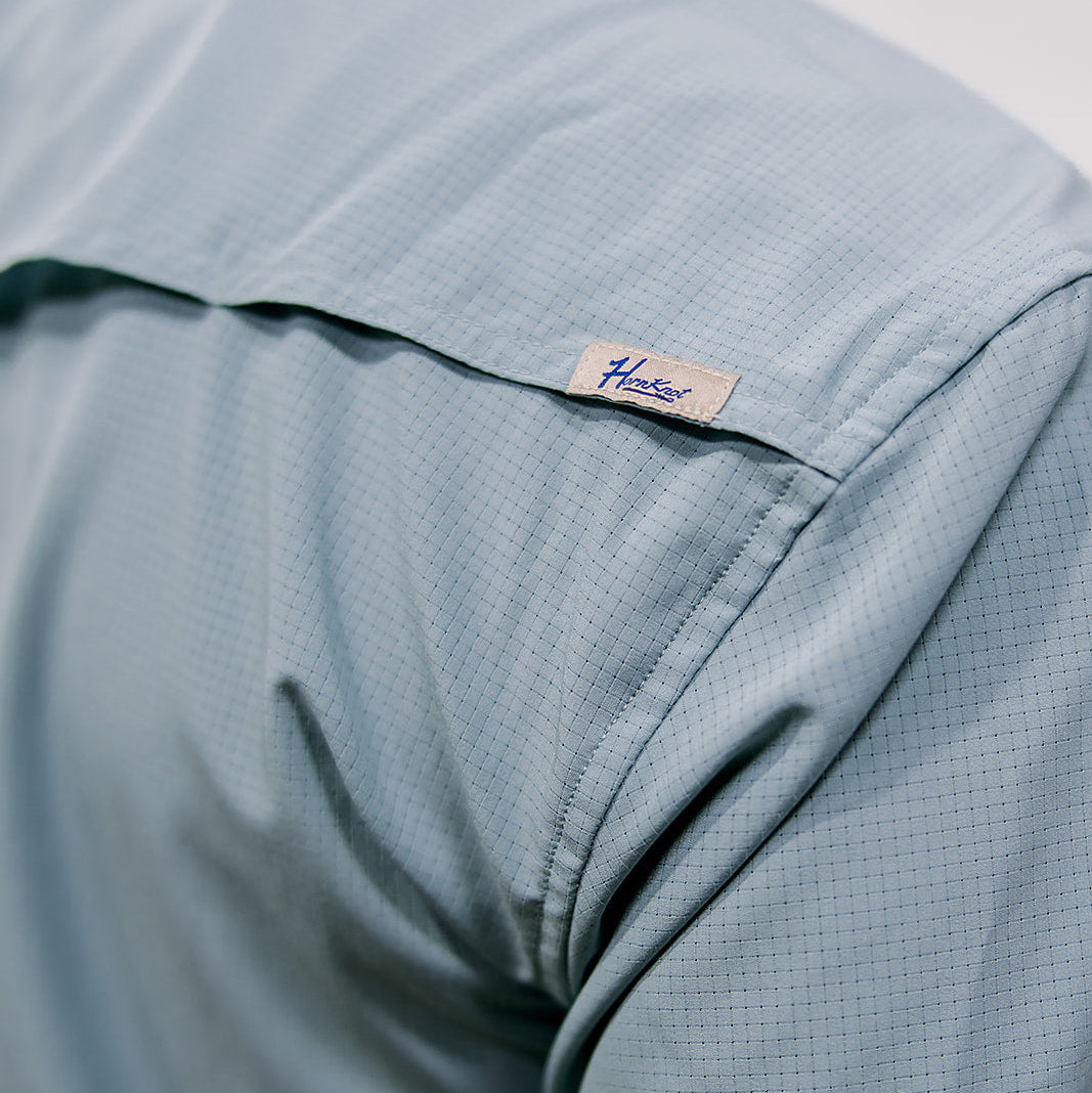 Close-up of a light blue shirt with a 'Hornknot' brand label on a white background