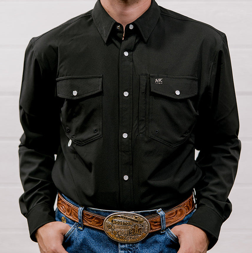 Man wearing a black shirt and blue jeans with a brown belt and large buckle against a white background. Front Facing.