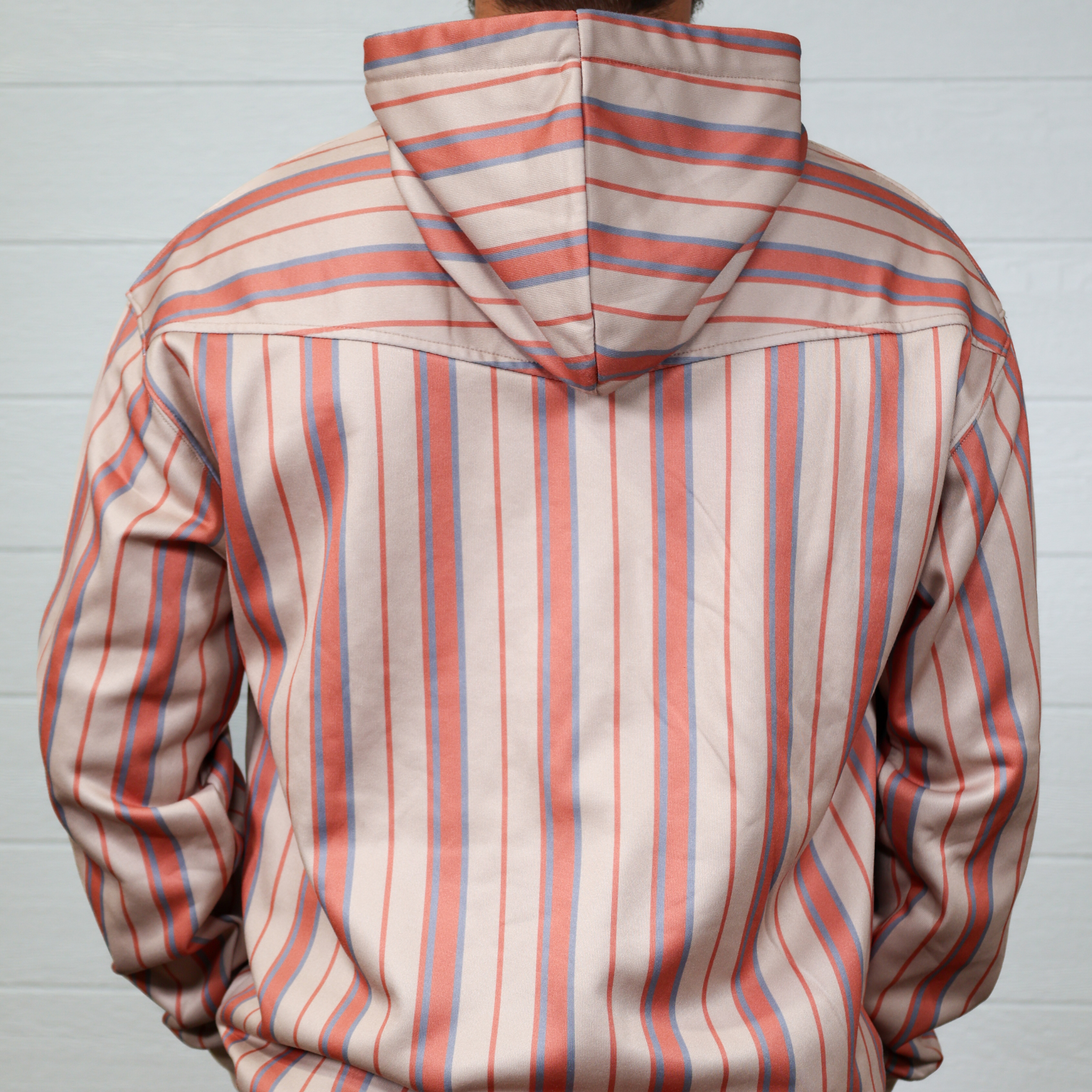 Person wearing a striped hoodie with red and blue lines on a plain background showing the back 