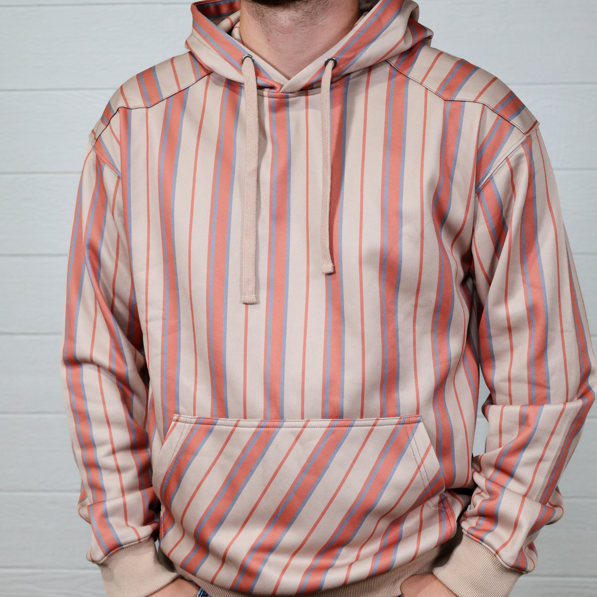 Person wearing a striped hoodie with red and blue horizontal stripes on a plain background showing the front
