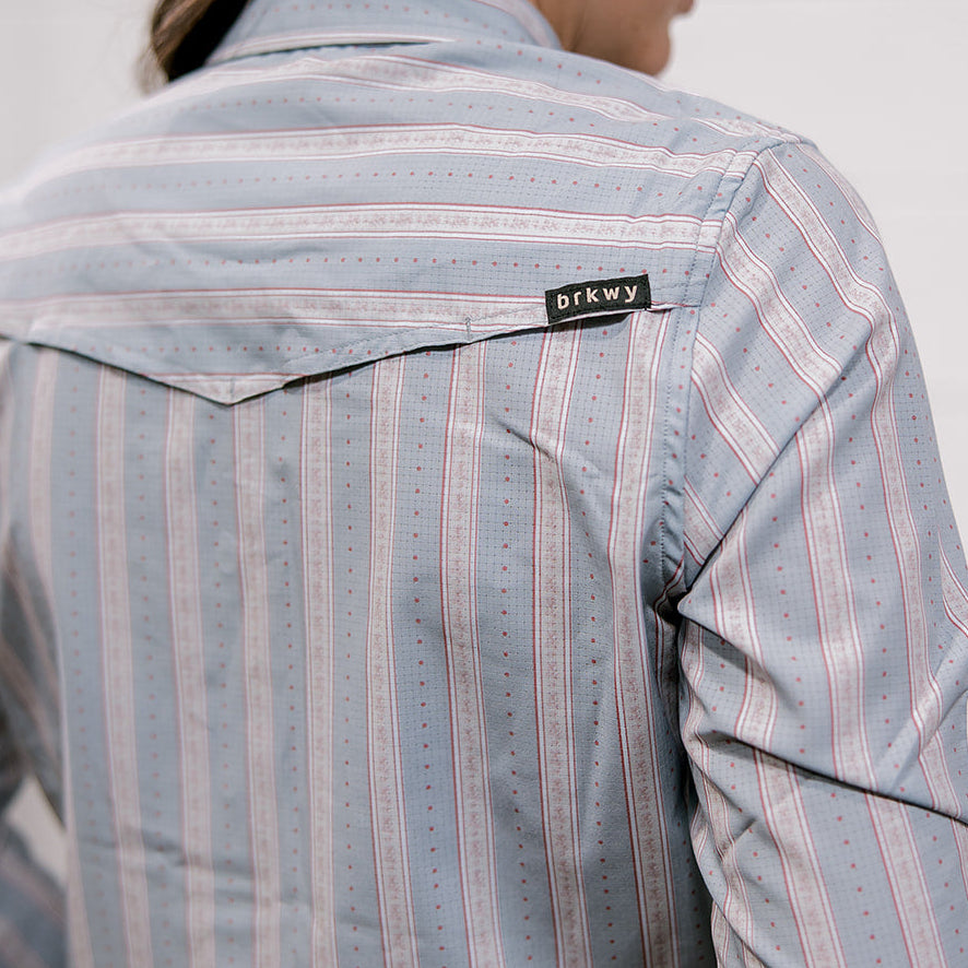 Person wearing a striped shirt with a visible brand label 'brkwy' on a plain background and showing the back vent 