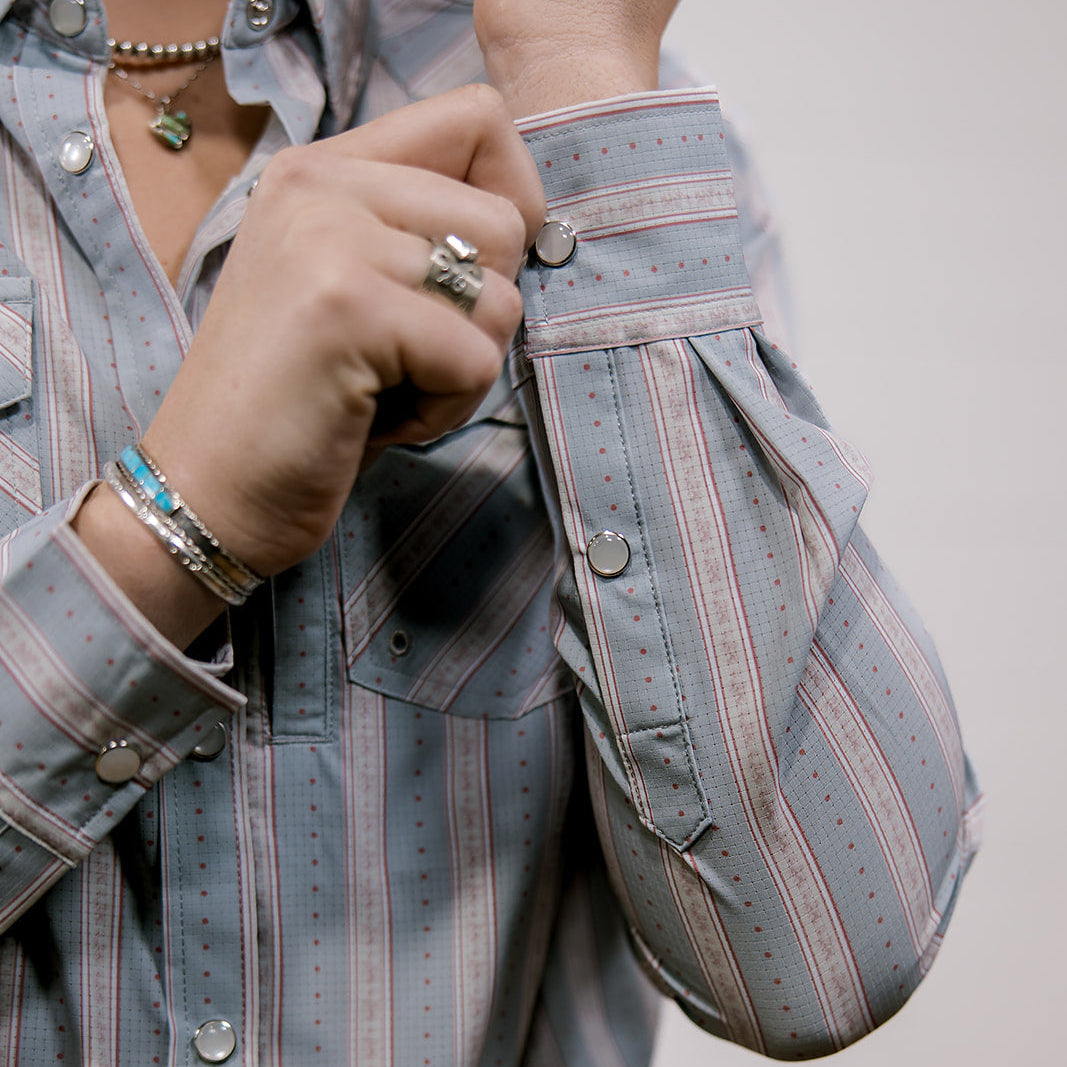 Person wearing a striped shirt with rolled-up sleeves showing the buttons 