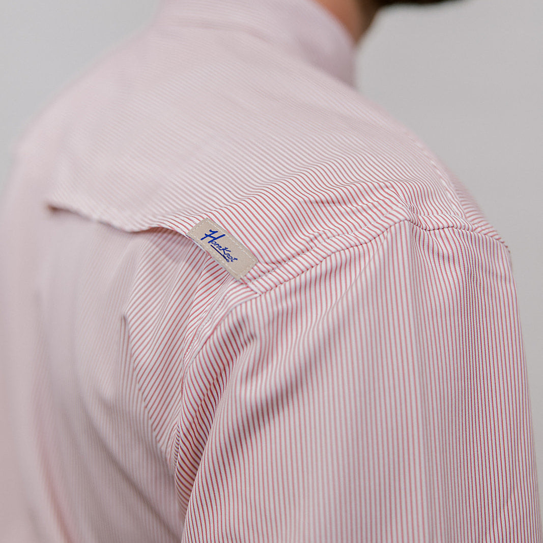 Close-up of a mauve striped shirt with a brand label on a plain background