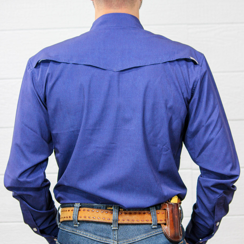 A man viewed from behind wearing a royal blue long-sleeve western shirt tucked into blue jeans, with a brown leather belt and a black holster containing a yellow handgun.