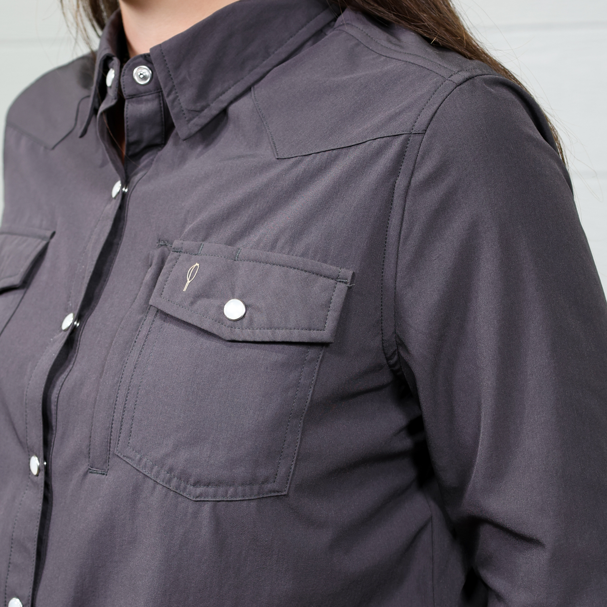 Close-up of a dark gray women's button down with button details on a plain background