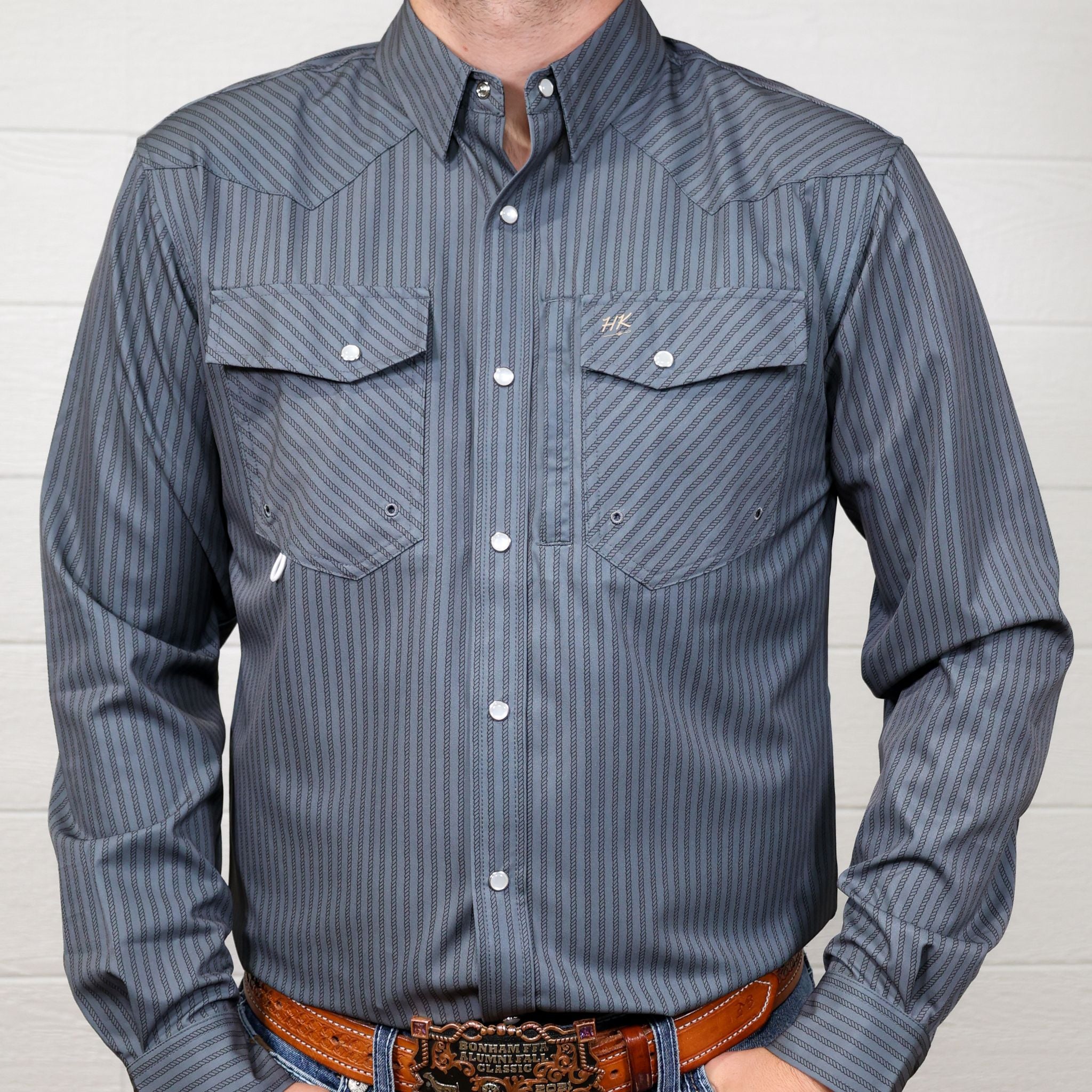 Grey striped shirt with two front pockets and pearl snaps on a white background