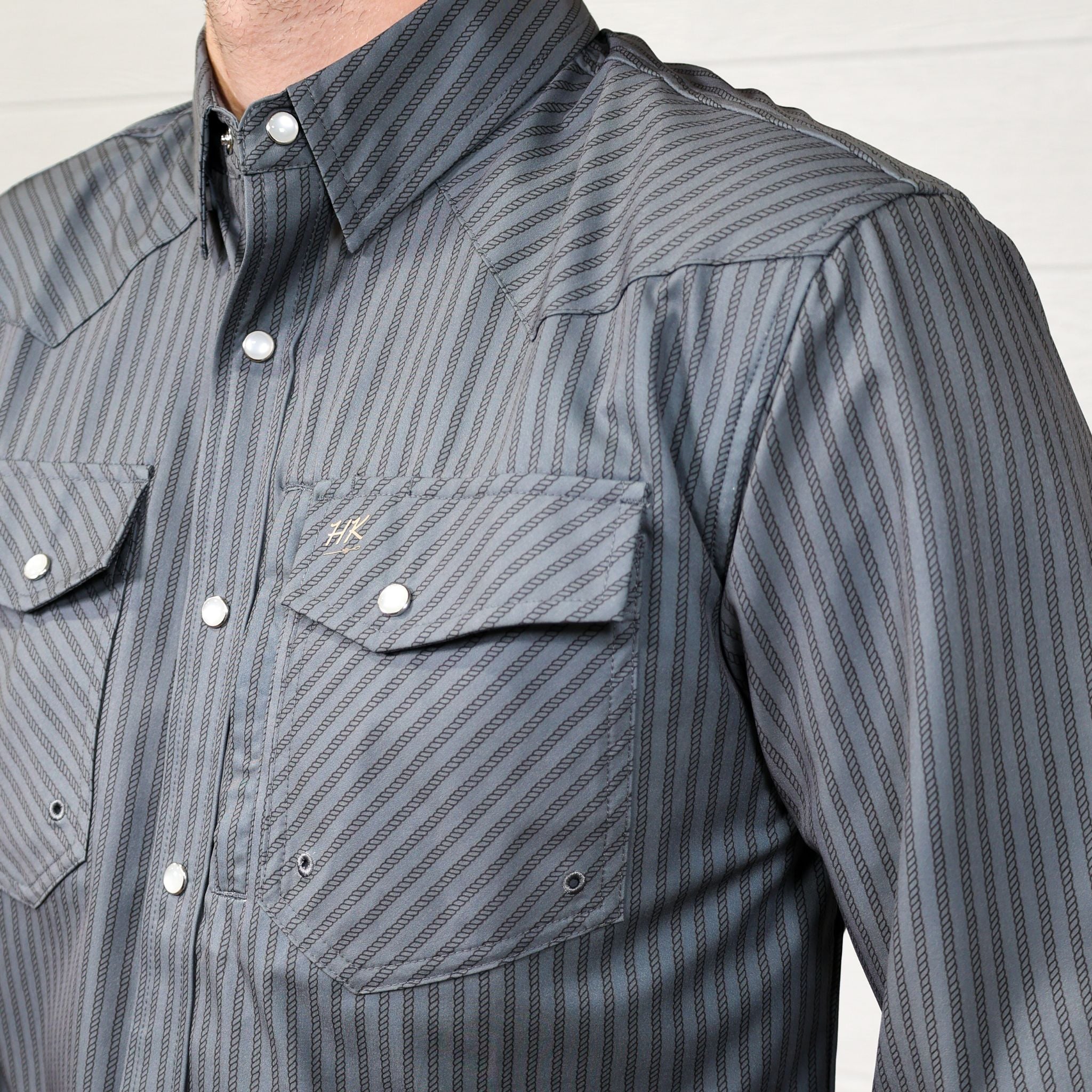 Detail Grey striped shirt with two front pockets and pearl snaps on a white background