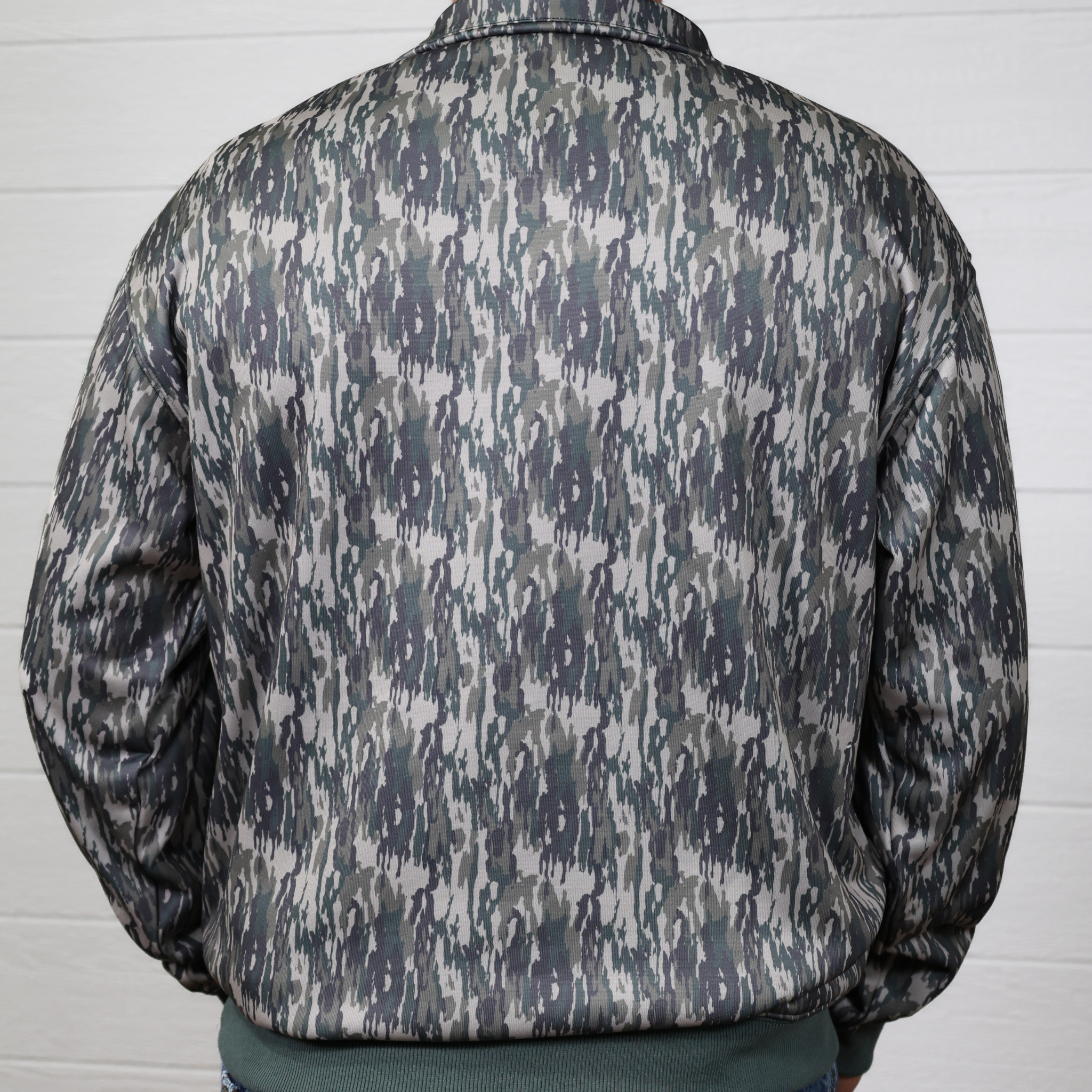 Camouflage jacket worn by a person against a white wall showing the back
