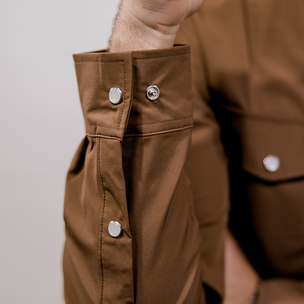Close-up of a brown shirt with button details on a plain background