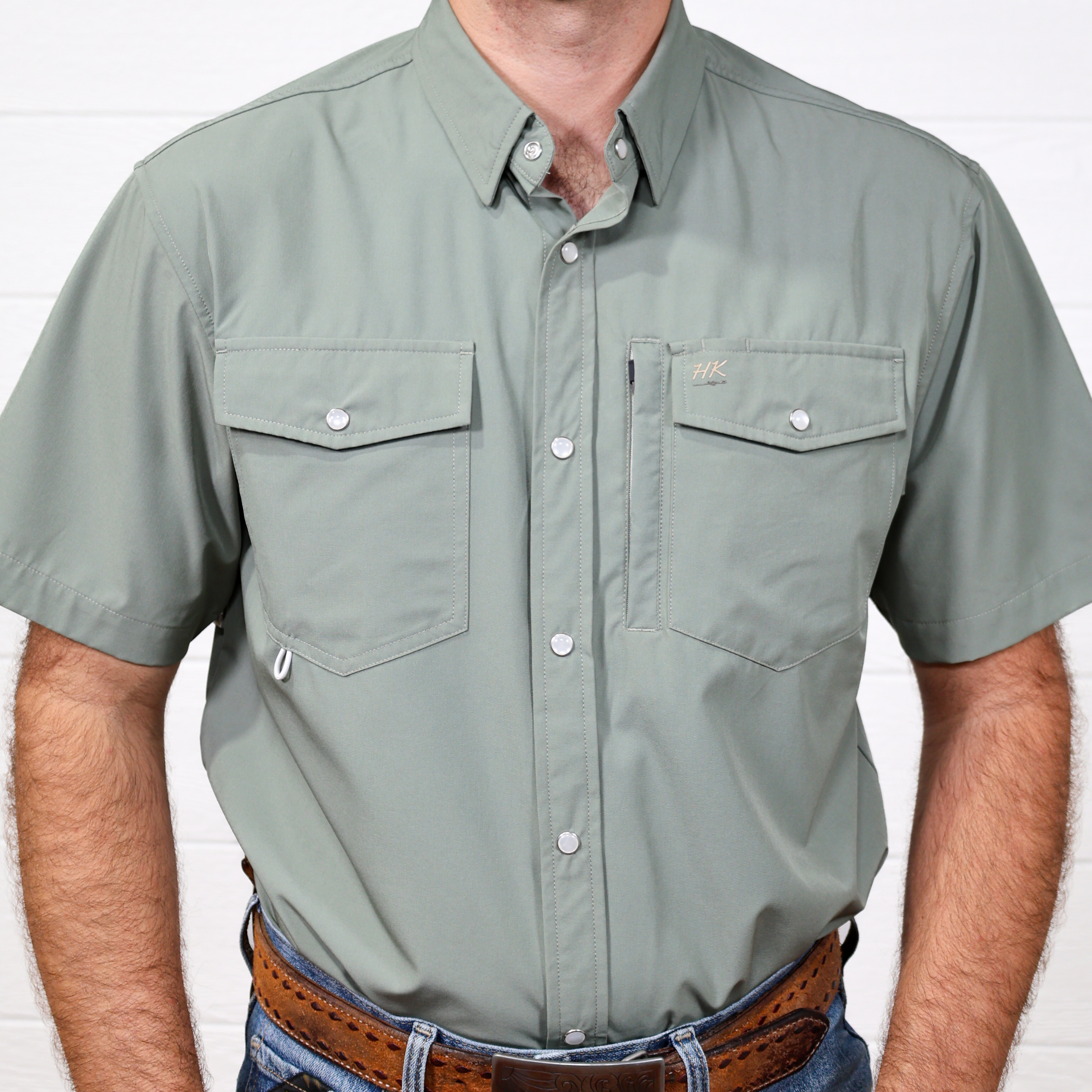 Man wearing a green short-sleeve shirt with pockets on a white background showing the front 